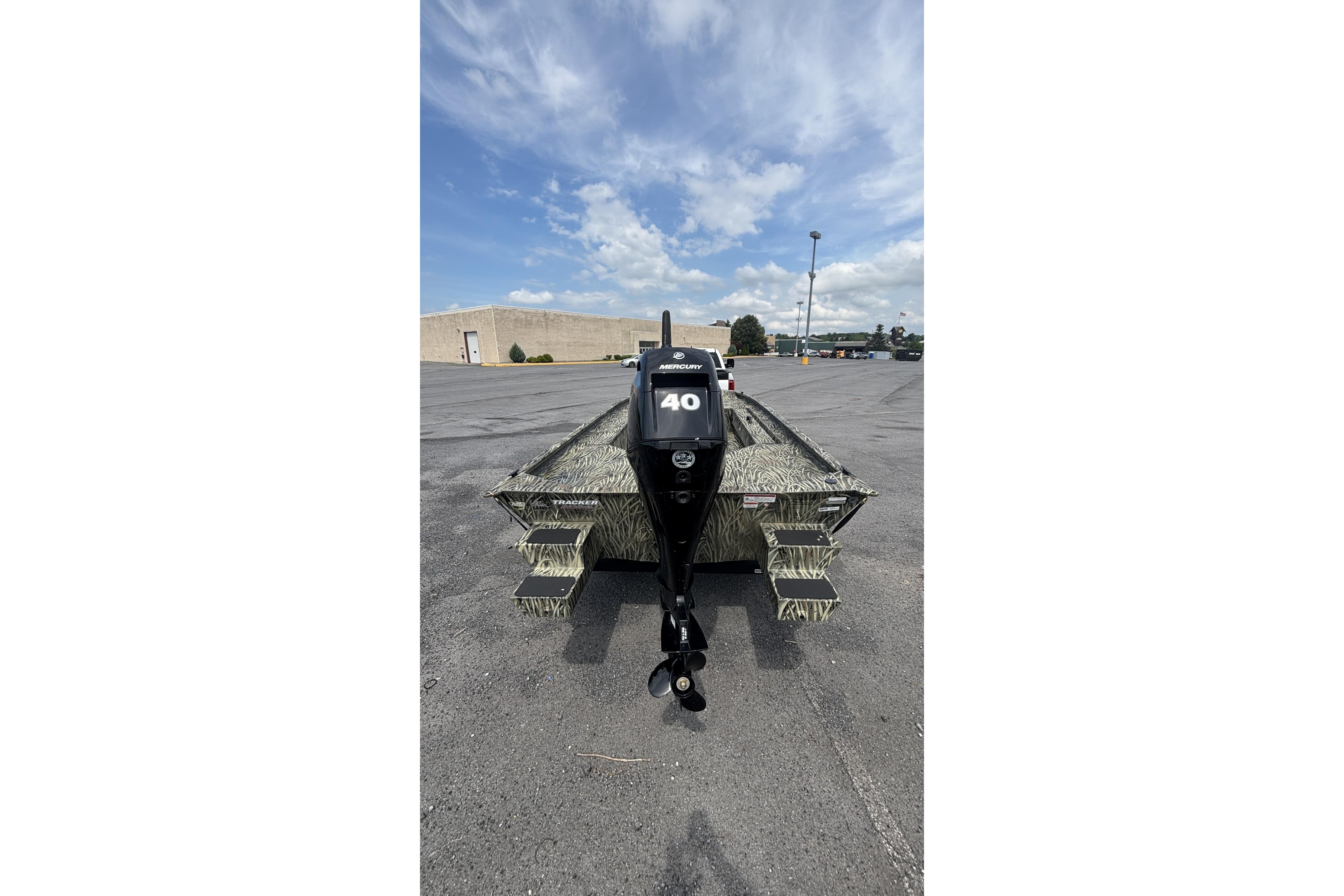 2026 Tracker Grizzly 1654 T Sportsman boat with Mercury engine in parking lot.