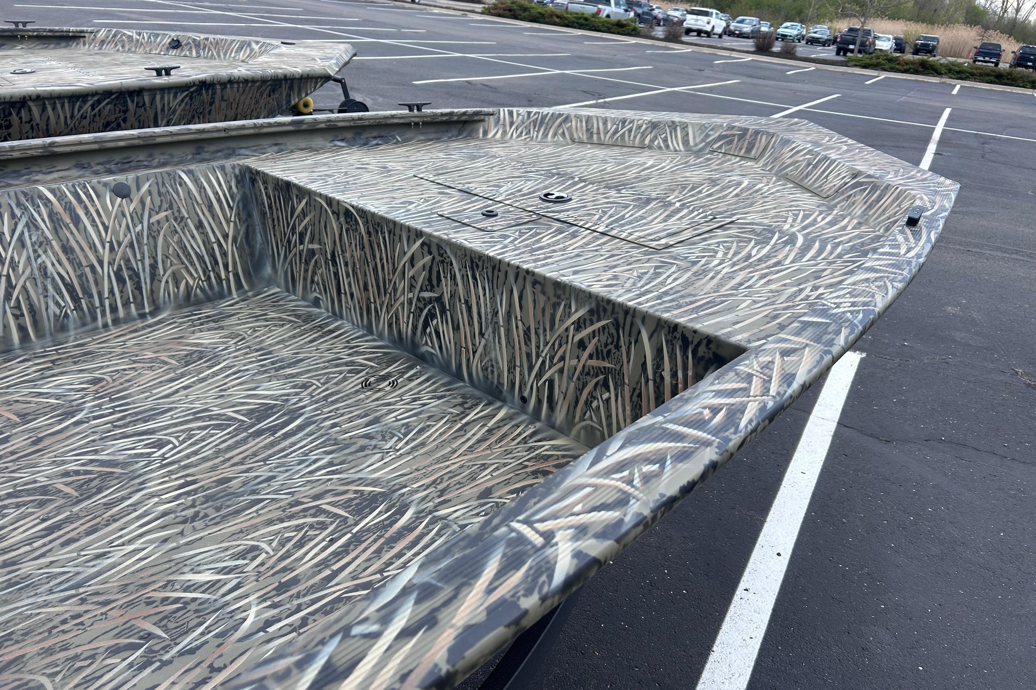 2026 Tracker Grizzly 1648 Utility boat with camouflage pattern in a parking lot.