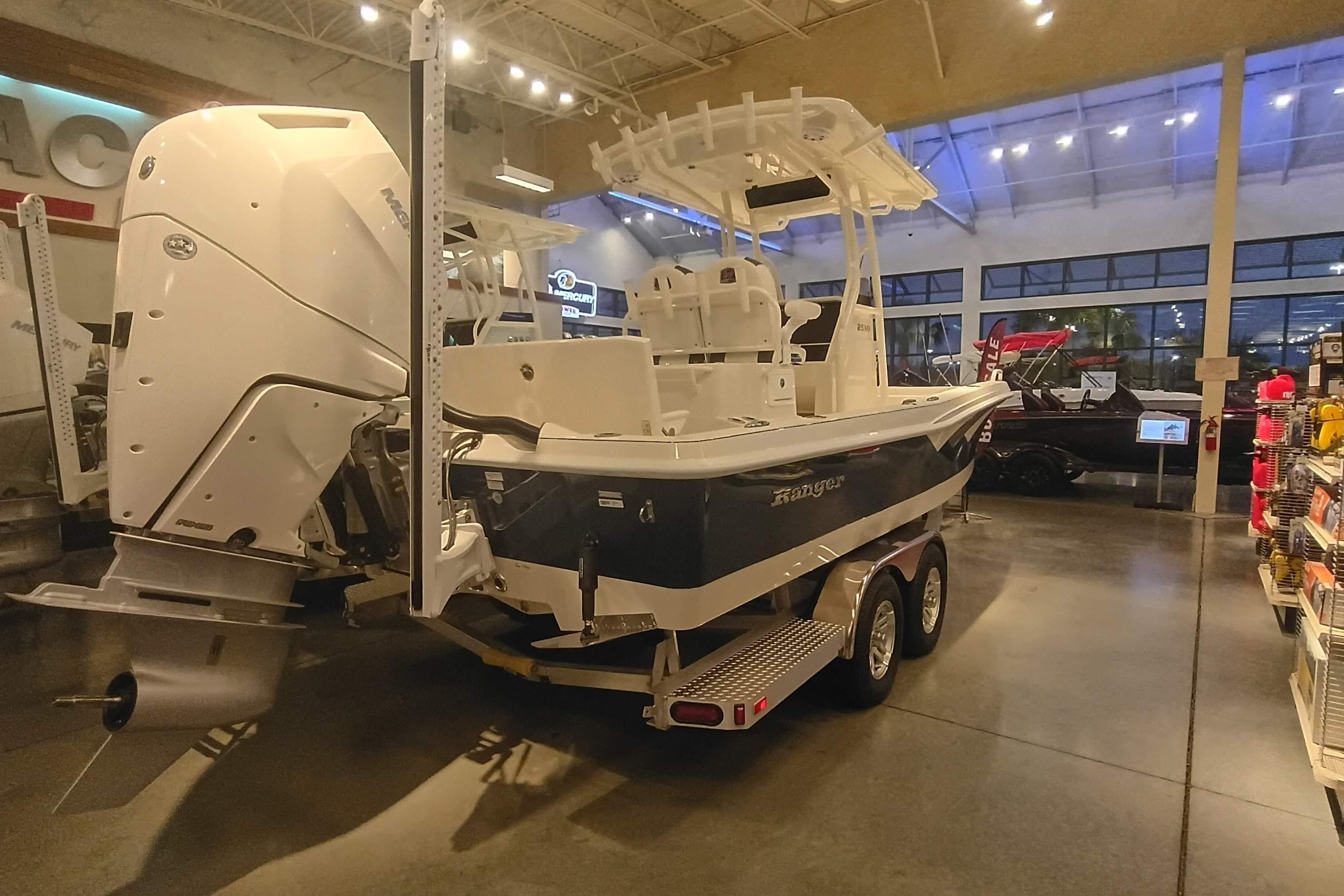 2025 Ranger 2510 Bay boat displayed indoors with powerful outboard motor.