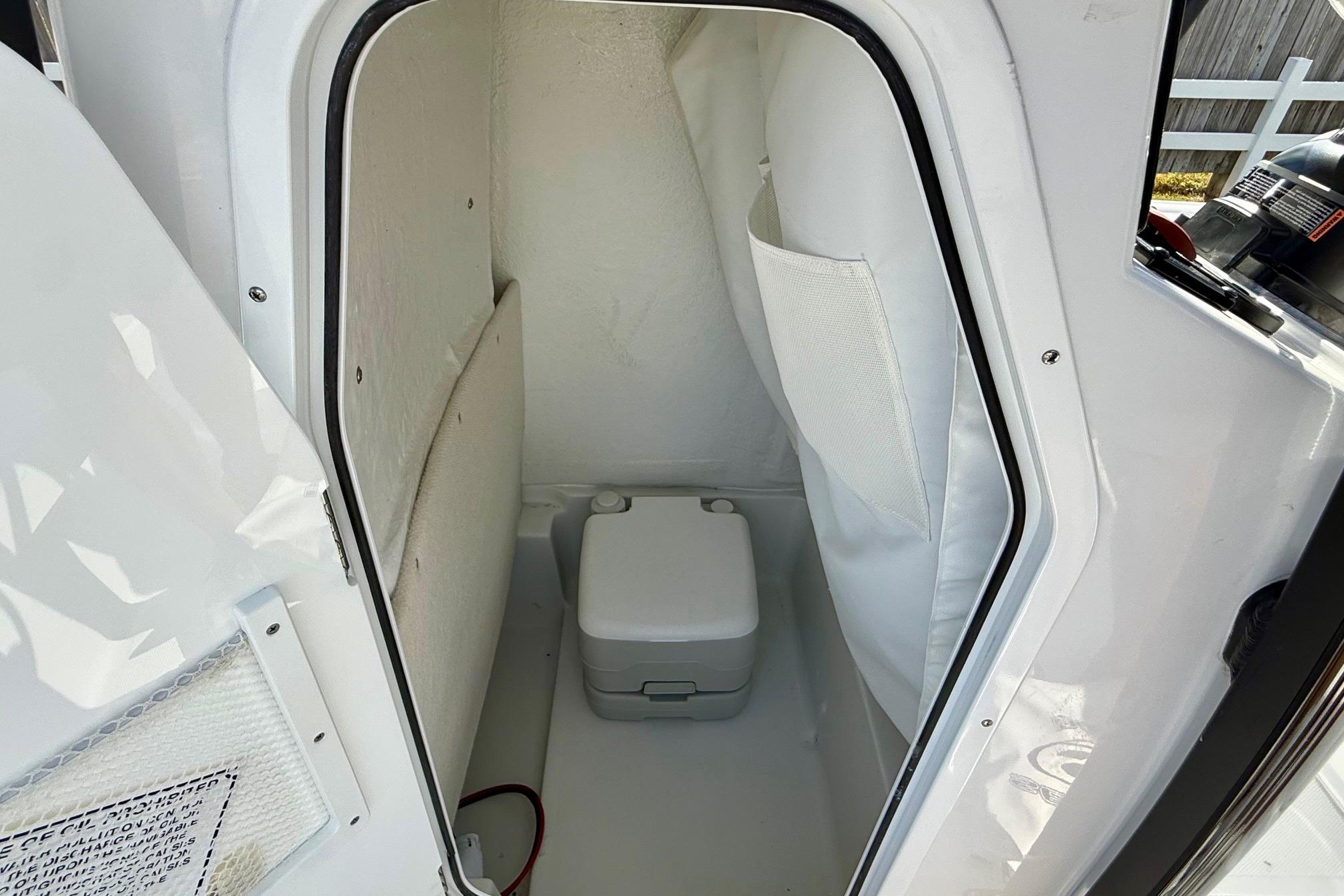 2026 Sea Hunt BX 22 BR boat interior with compact toilet and storage area.