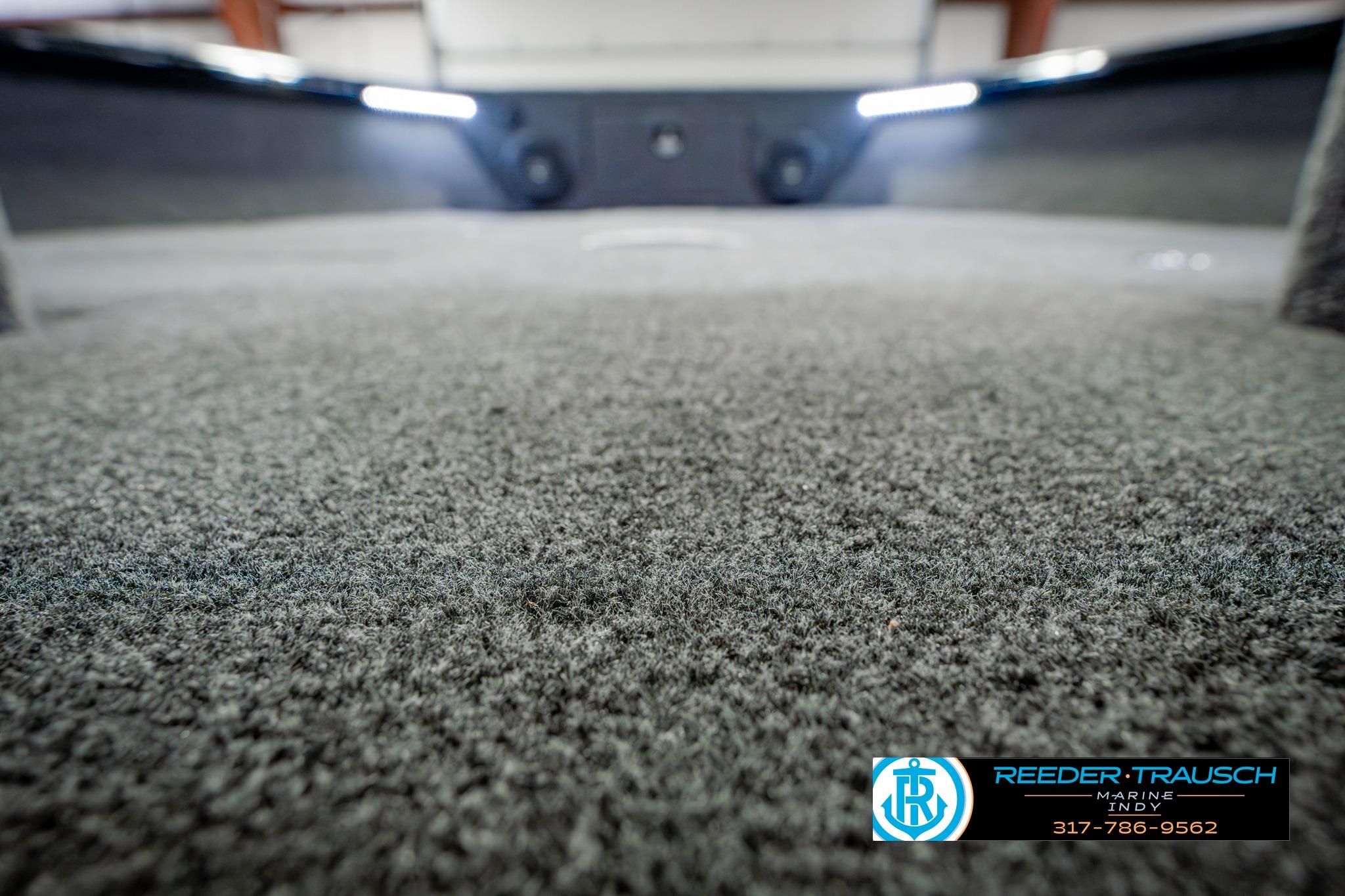 2026 Lund 1875 Impact XS boat interior with carpeted flooring and ambient lighting.