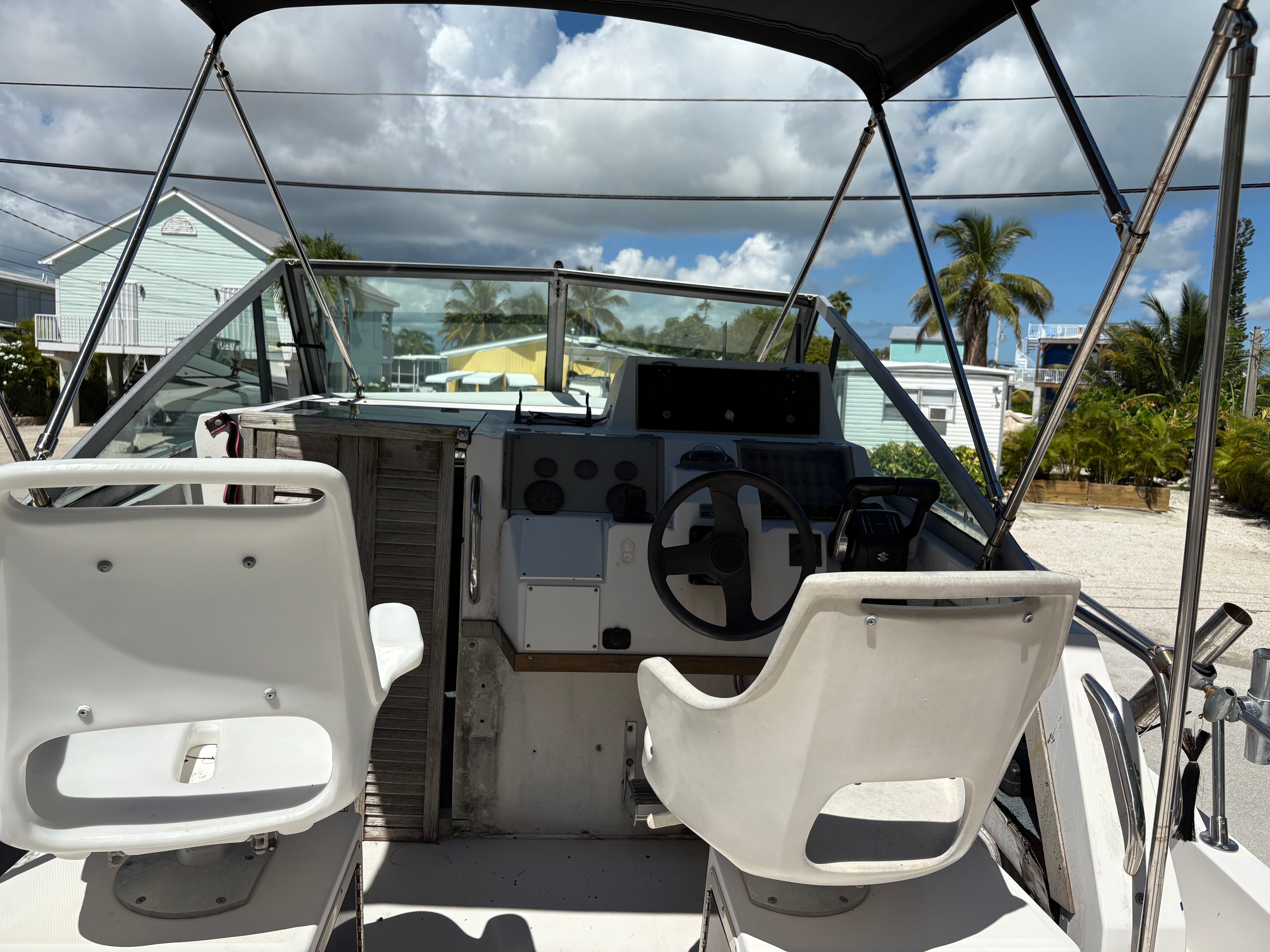 The cockpit of a 1990 Grady-White Sailfish with two white seats and a helm station.