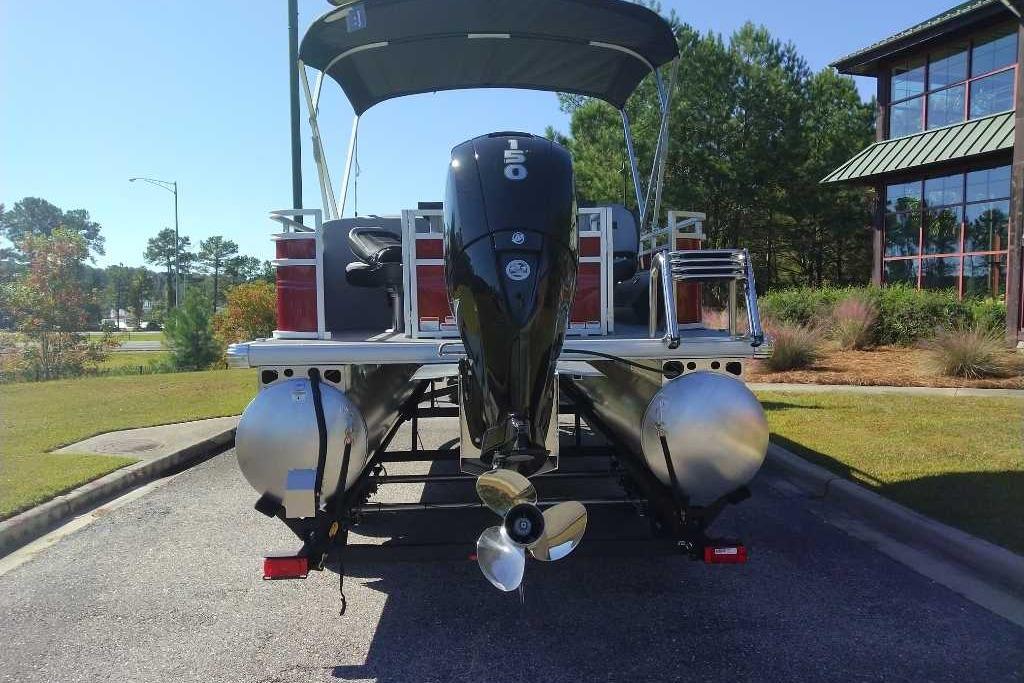 2026 Sun Tracker SportFish 22 DLX pontoon boat with powerful outboard motor, parked outdoors.