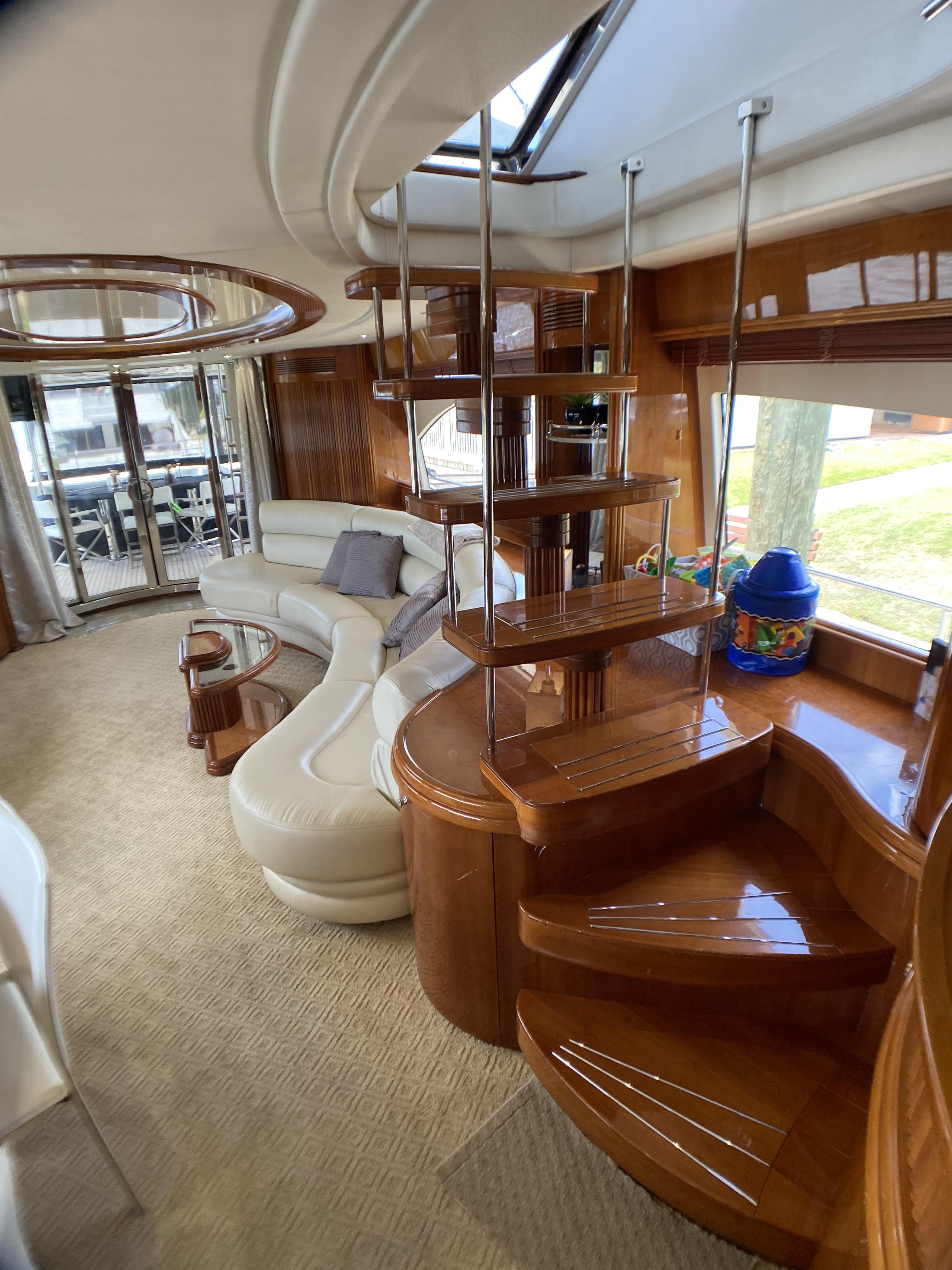 Luxurious interior of 1999 Azimut 85 Ultimate yacht with elegant wooden staircase and plush seating.