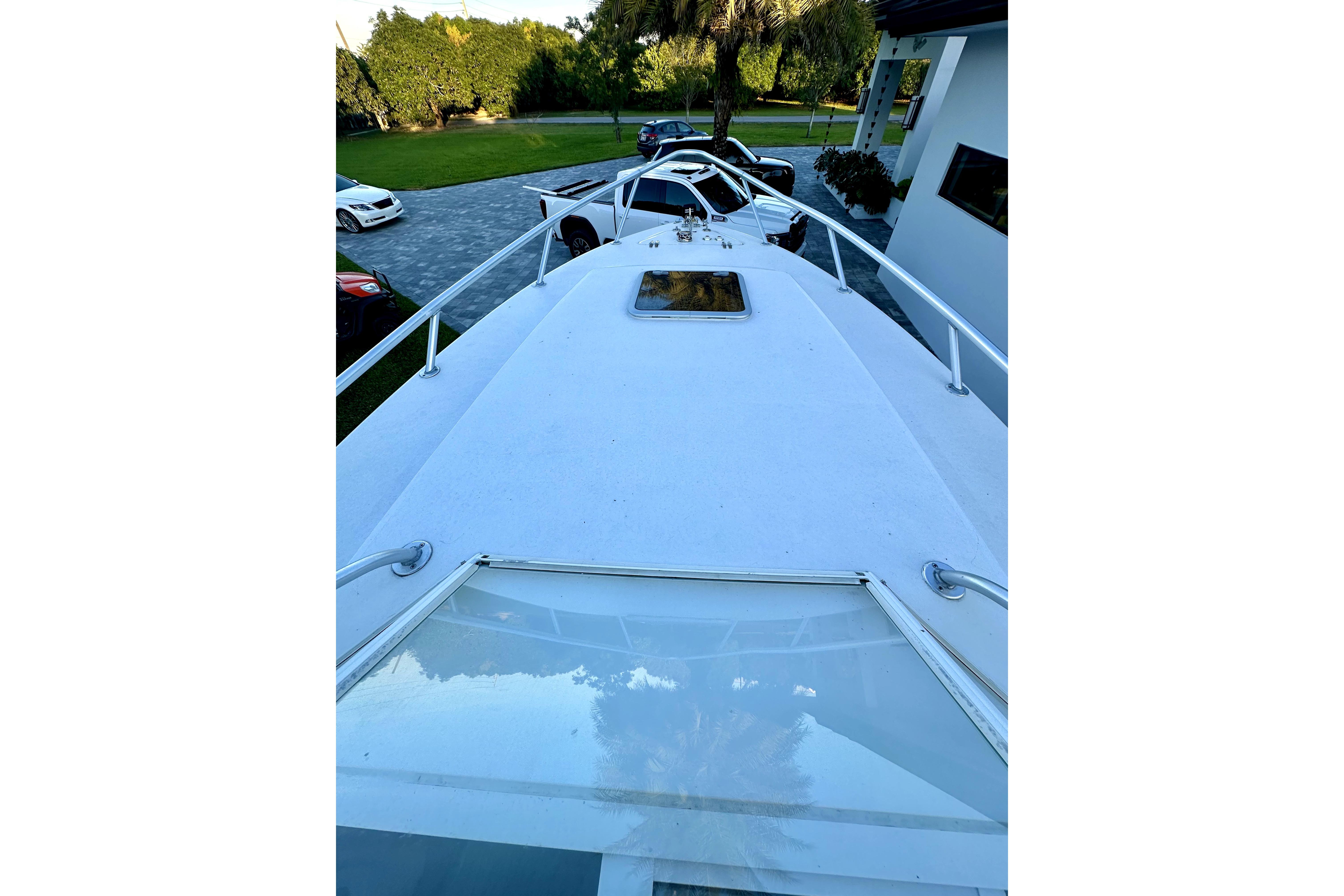 2006 Contender 35 Express Side Console boat on driveway, surrounded by cars and greenery.