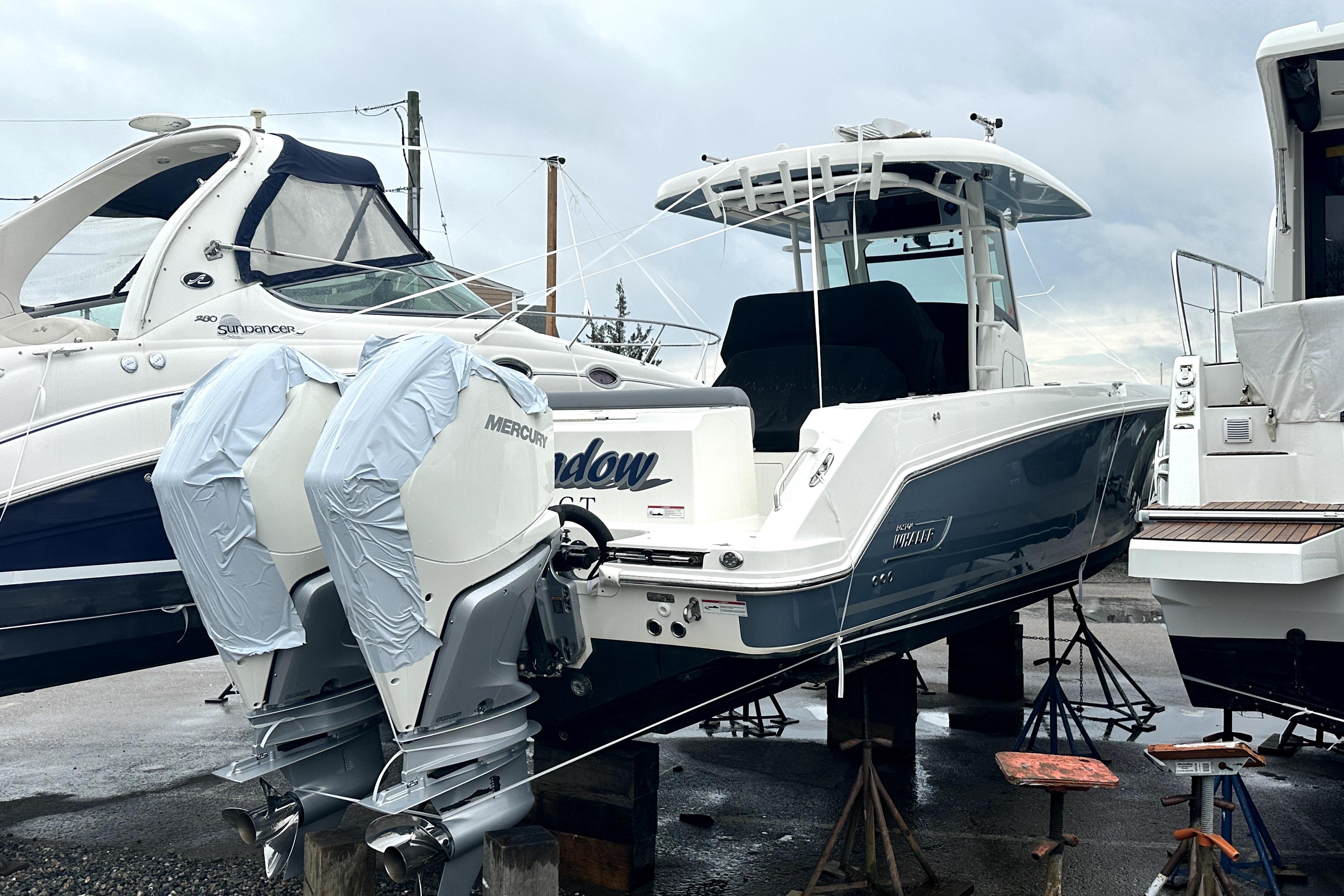 2023 Boston Whaler OUTRAGE boat with twin Mercury engines on a dock.