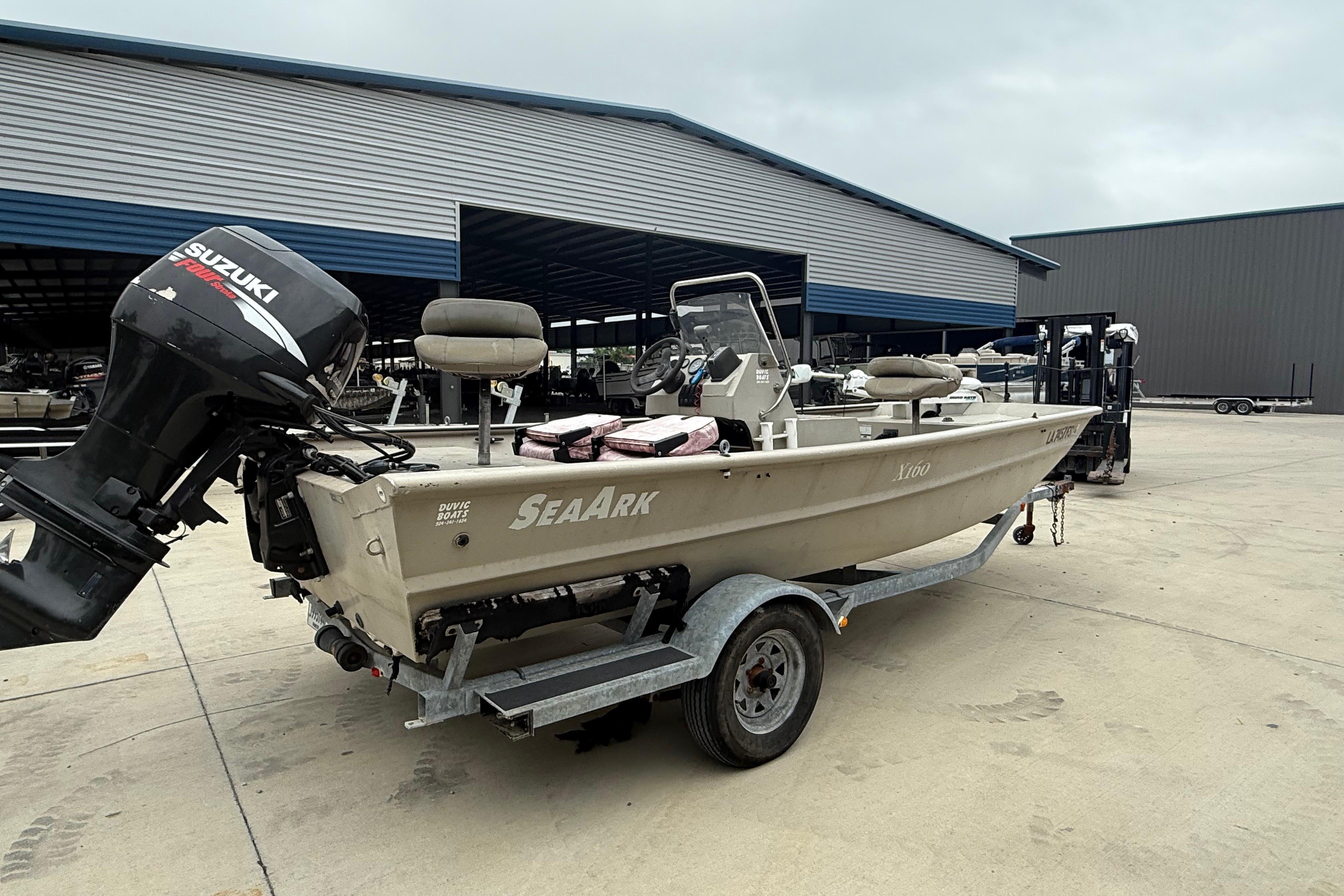2008 SeaArk 1652 MV boat on trailer with Suzuki outboard motor, parked outdoors.