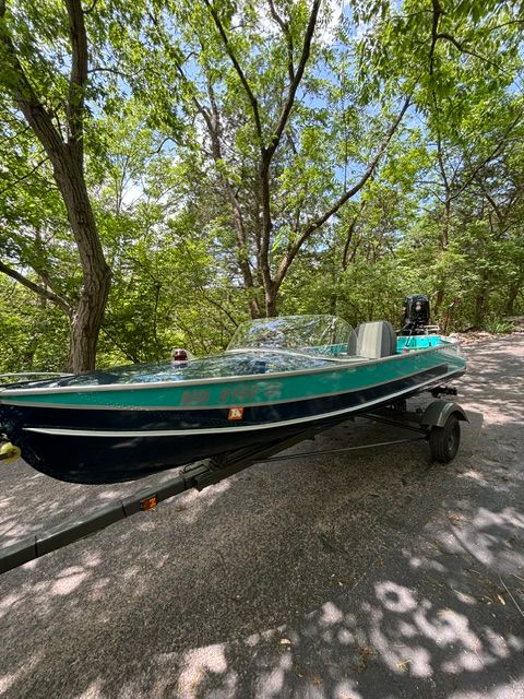 1958 Richline Knight Deluxe boat on a trailer in a wooded area.