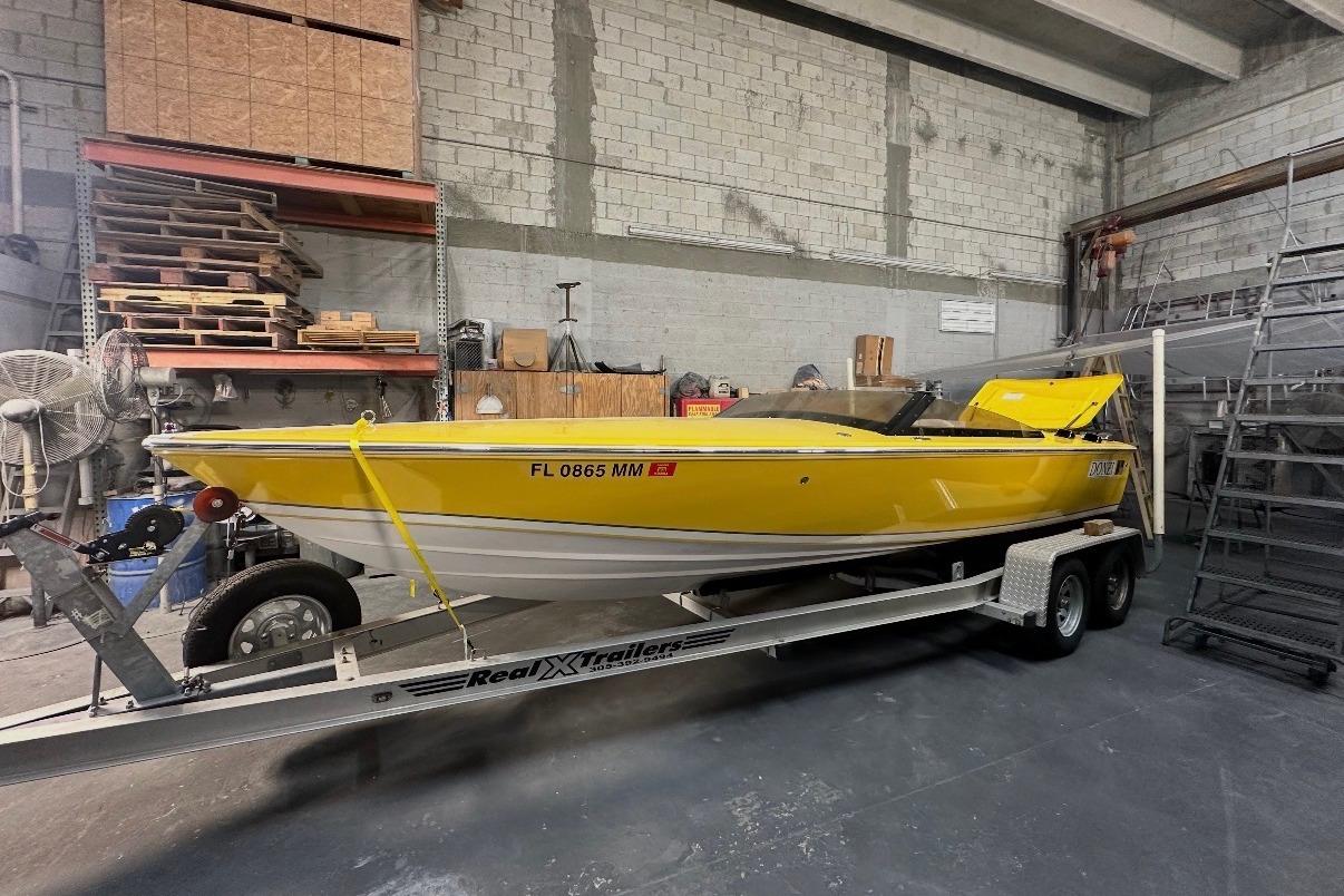 Yellow 2004 Donzi 22 Classic boat on trailer in a warehouse setting.