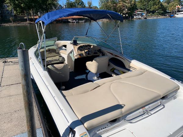 2000 Sea Ray 210 Bow Rider boat docked by a lake with blue canopy.