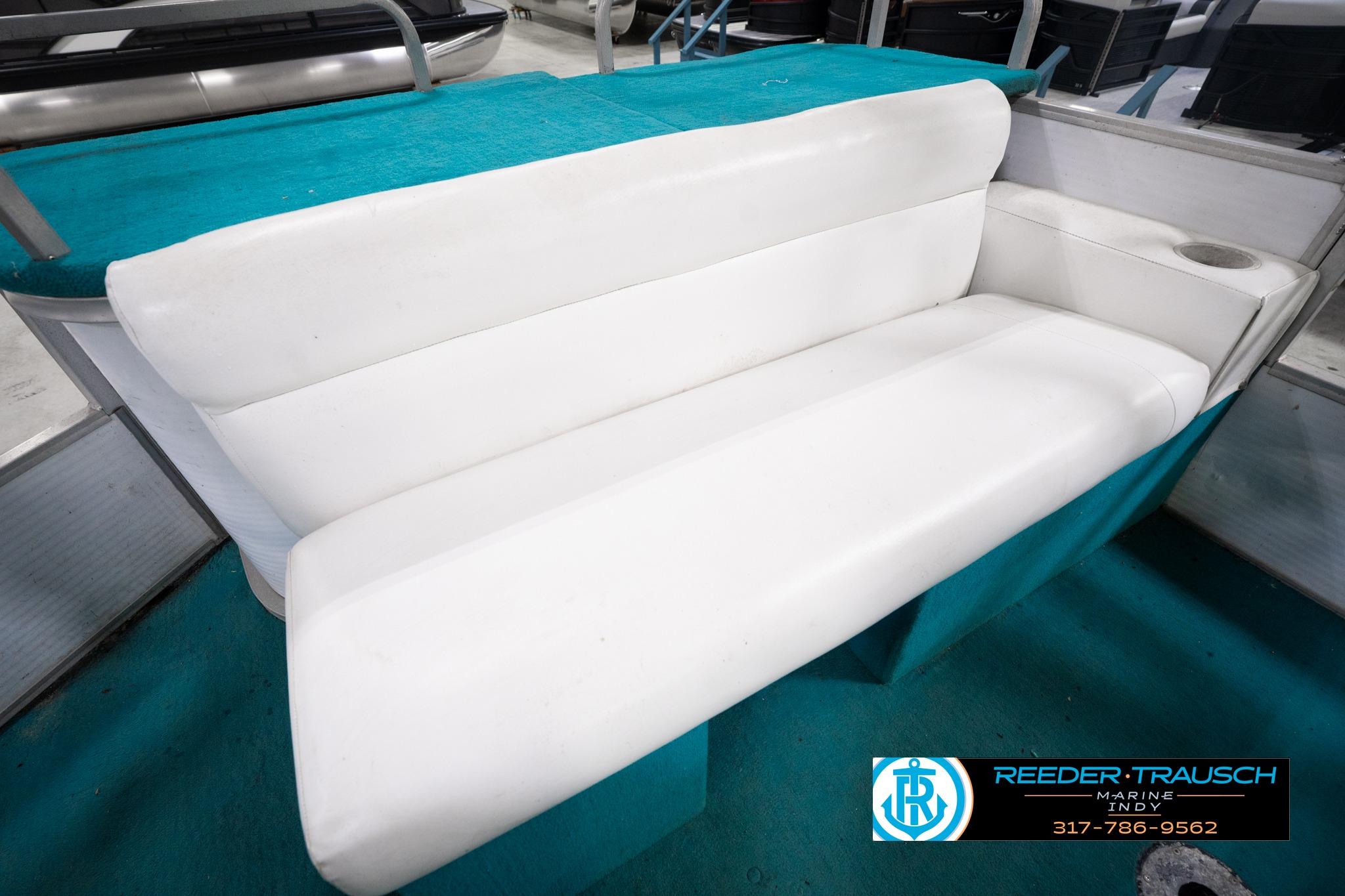 White seating on a 1992 Godfrey Sweetwater boat, featuring teal accents and cup holder.