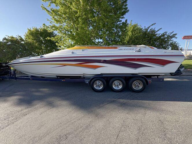 2002 Advantage Victory boat with vibrant graphics on a trailer, parked outdoors.