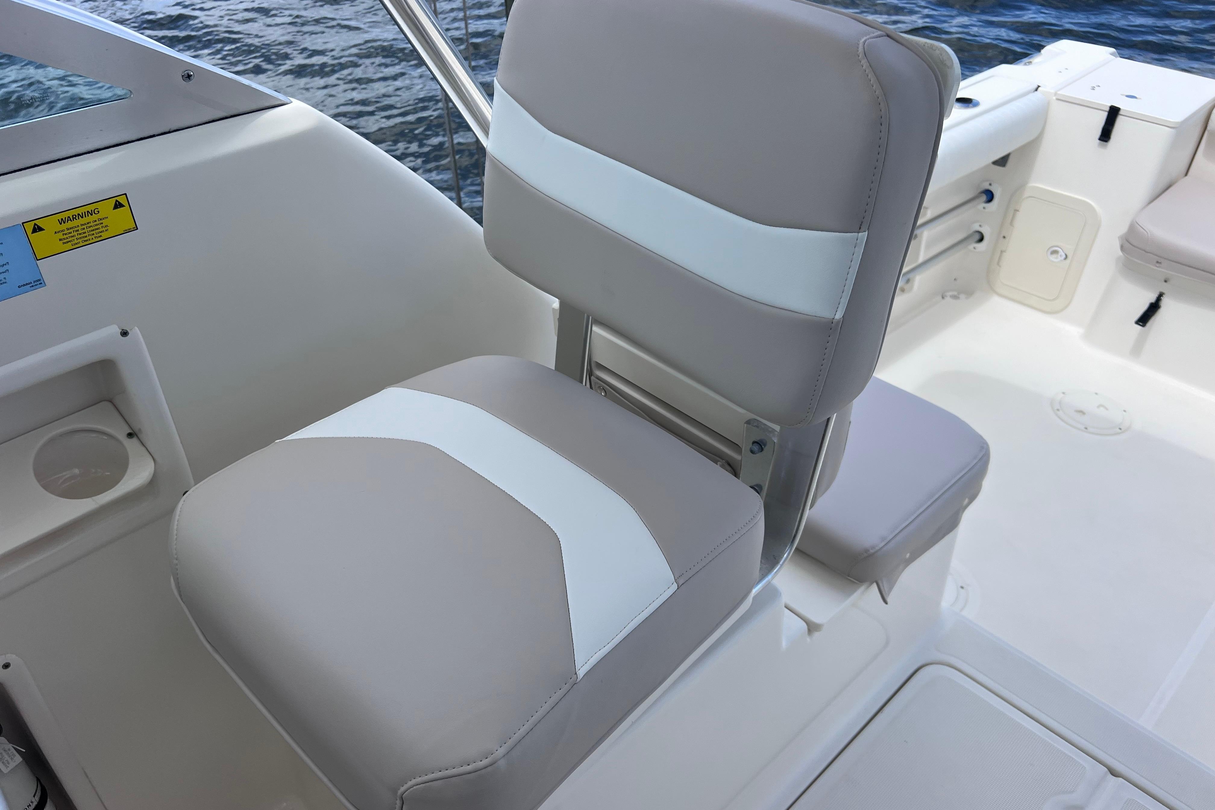 2004 Pursuit 2870 Walkaround boat seat with beige and white upholstery, near water.