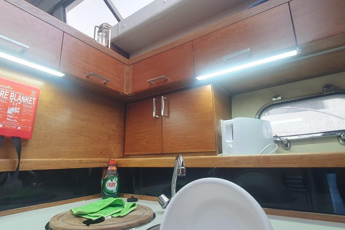 Compact kitchen area in a 1989 Princess 35 boat with wooden cabinets and modern amenities.