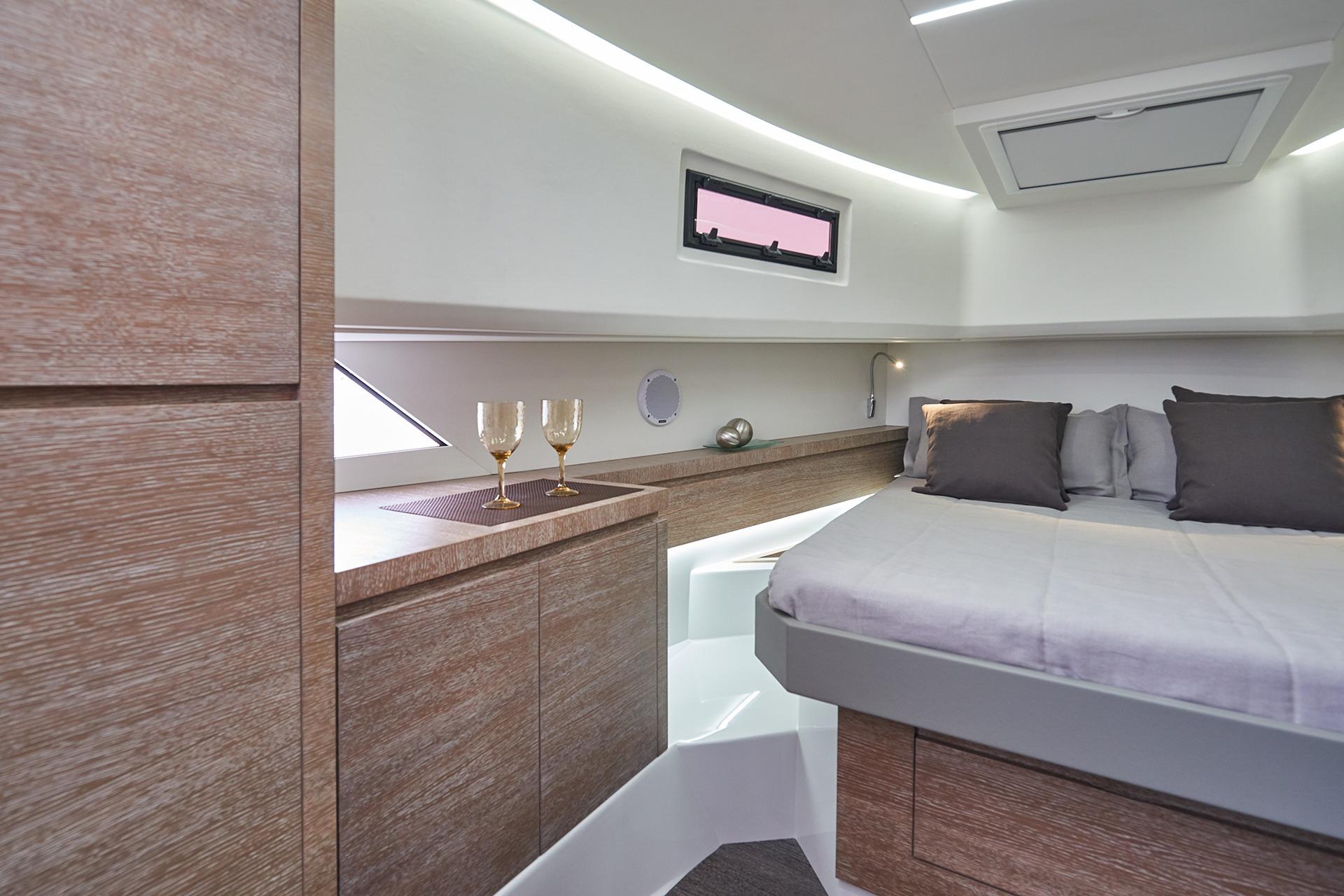 Luxurious interior of 2026 Astondoa 377 Coupe yacht with modern wood finish and cozy bedding.
