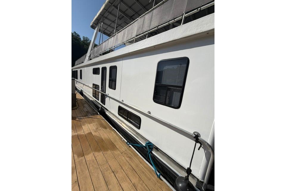 1997 Stardust Houseboat 18x83 docked, showcasing sleek white exterior and multiple windows.
