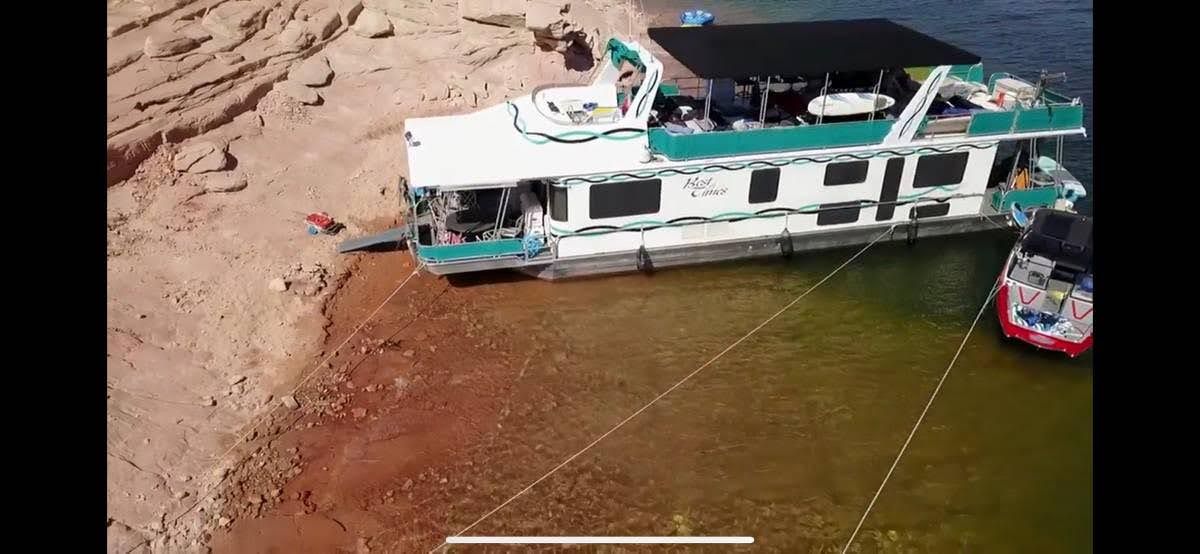 1993 Lakeview houseboat docked at rocky lakeside shore.
