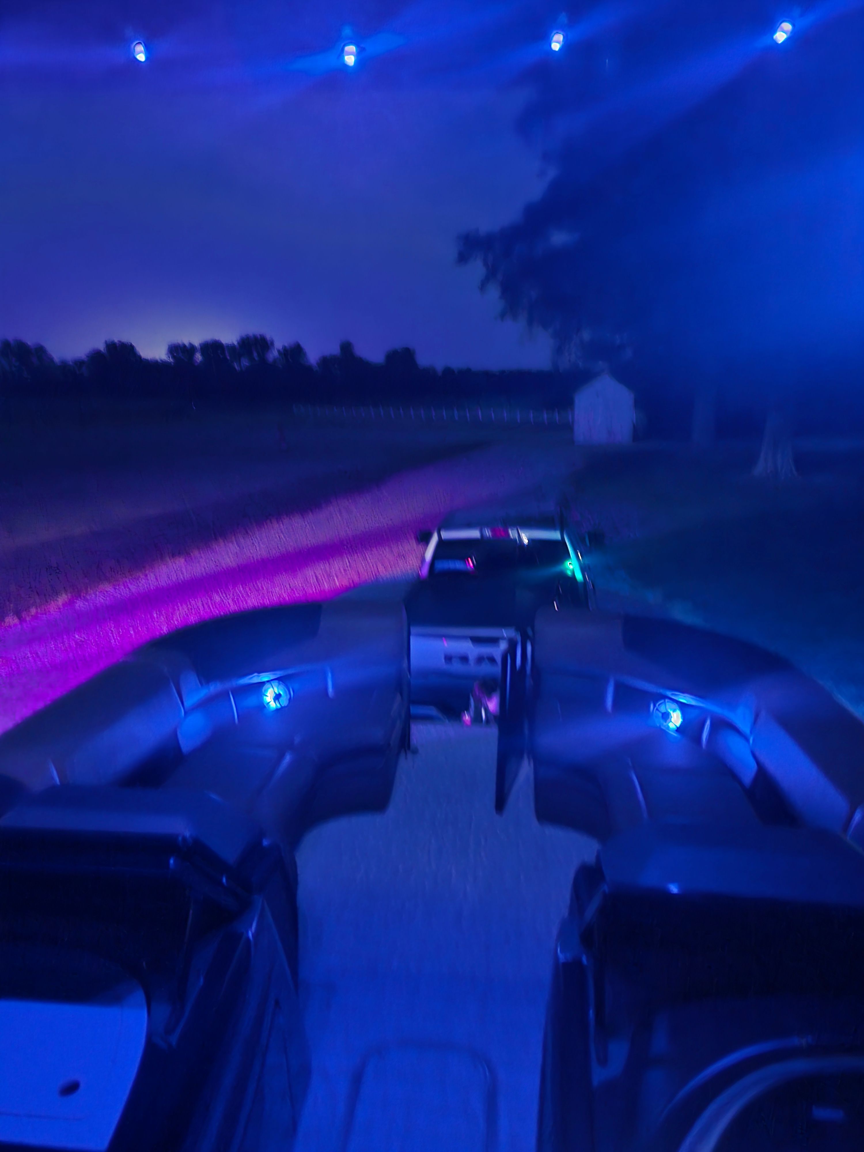 The image shows a boat illuminated at night with blue and purple lights.
