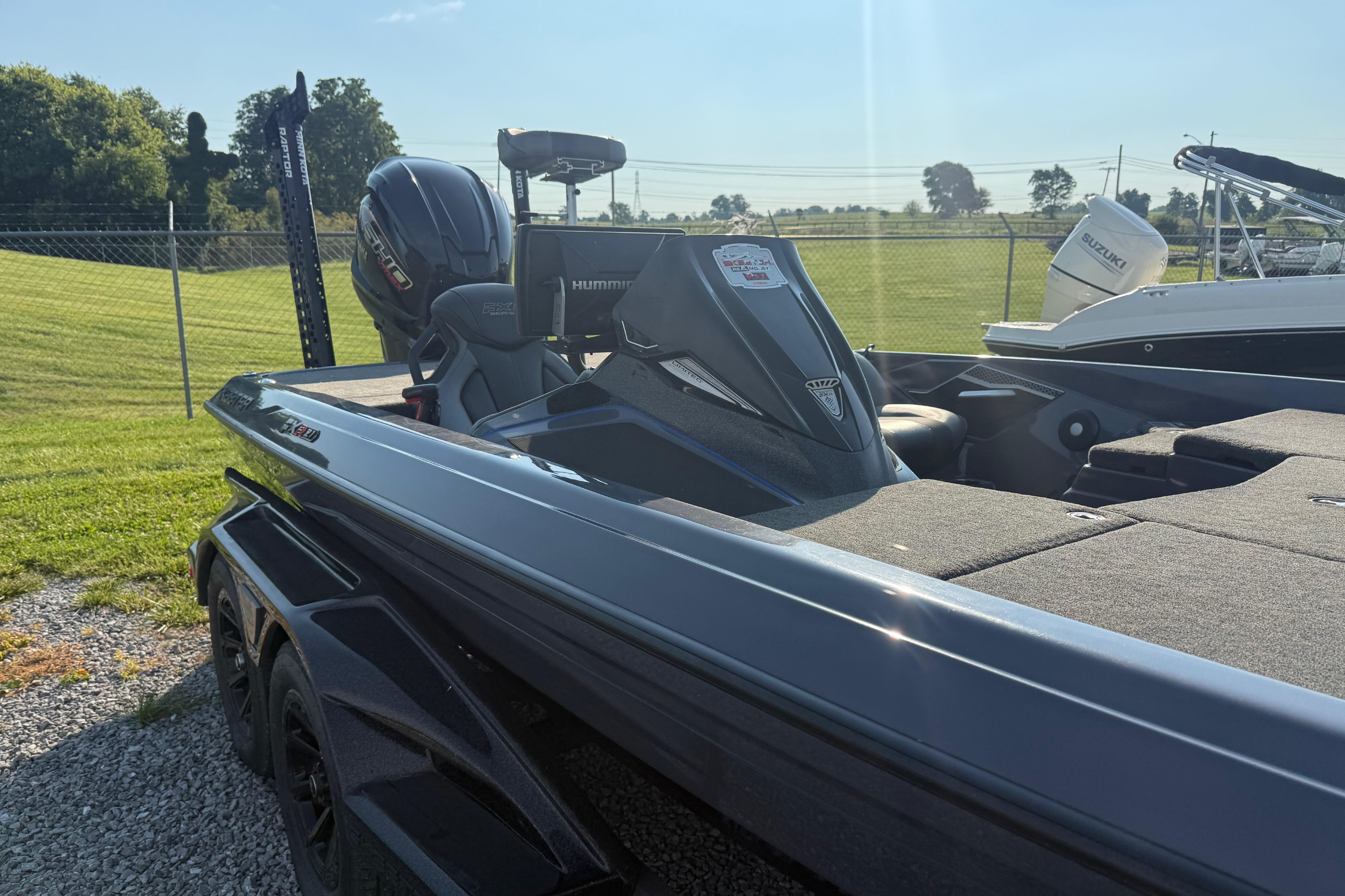 2024 Skeeter FXR21 boat with motor, parked on gravel, sunny day.