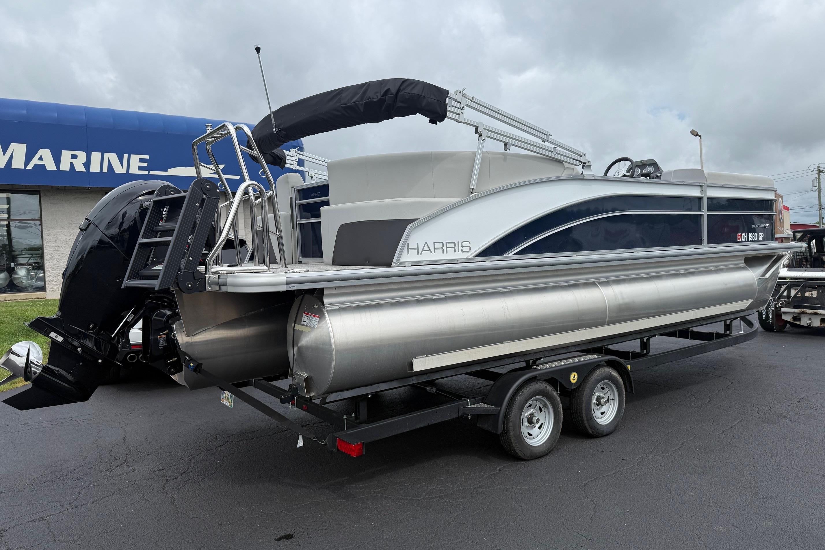 2025 Harris Cruiser 230 pontoon boat on trailer, displayed at a marine dealership.