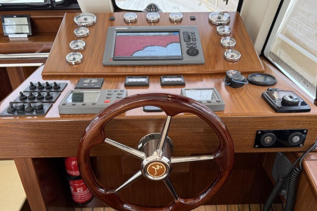 Steering console of 2012 Sasga Yachts Menorquin 42 with navigation instruments and wooden wheel.