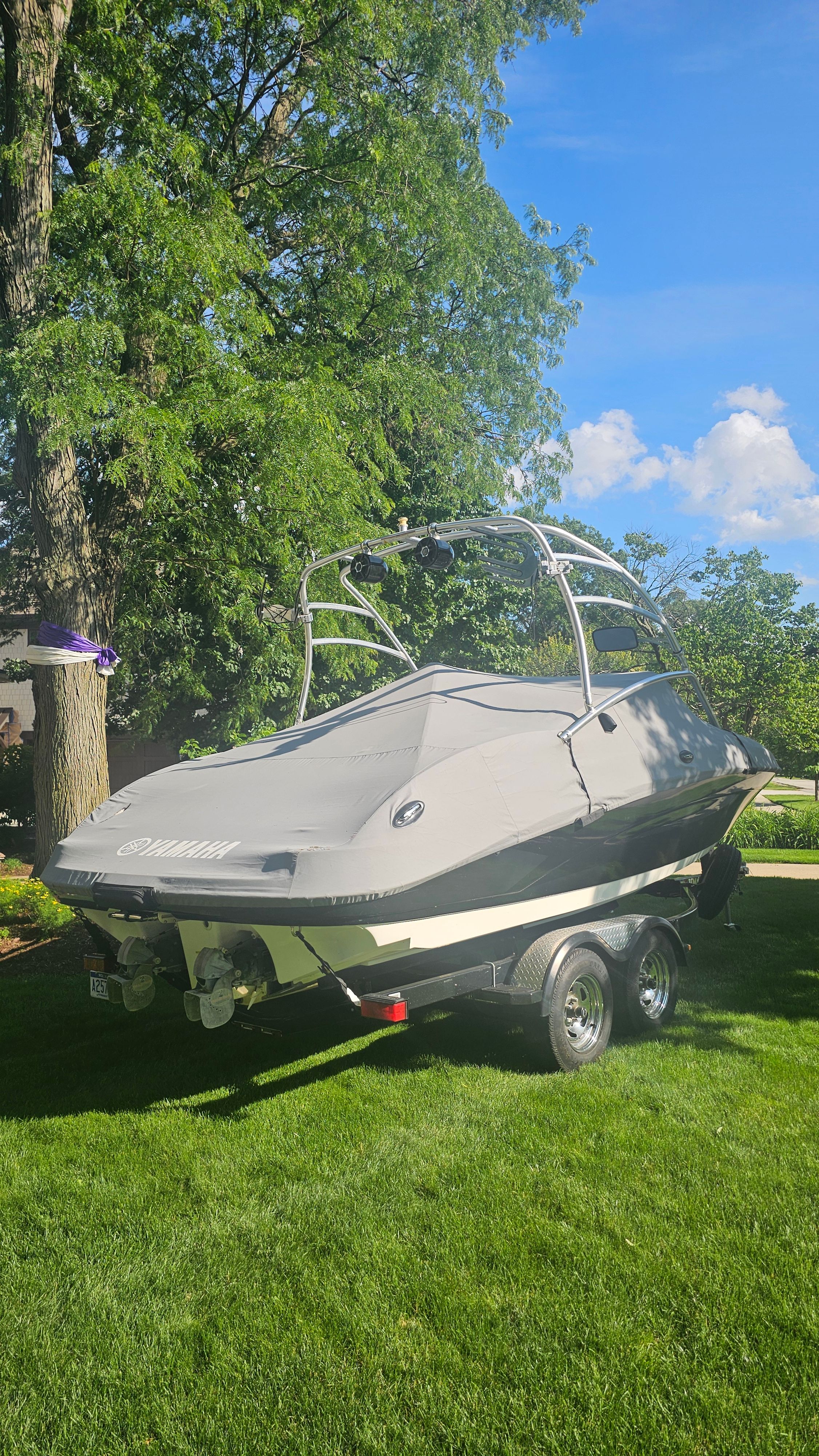 A 2010 Yamaha AR210 boat on a trailer, set on a green lawn.
