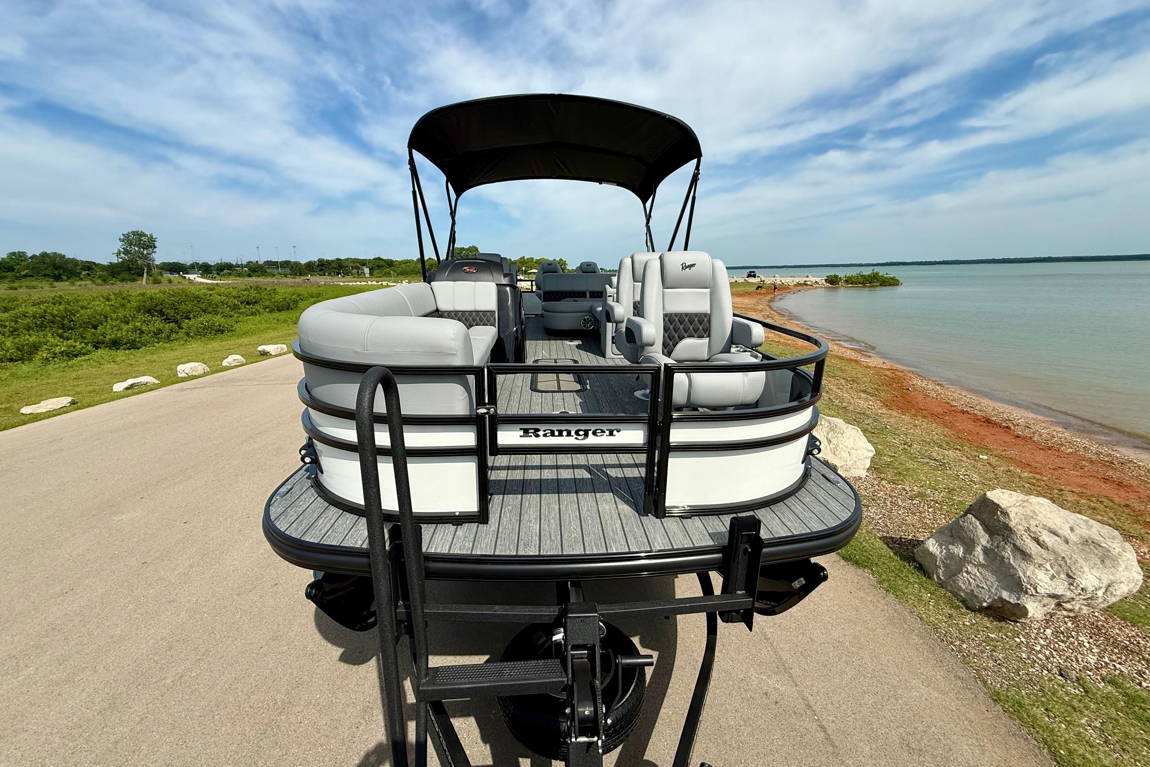 2026 Ranger 223FC pontoon boat parked by a scenic lakeside under a clear sky.