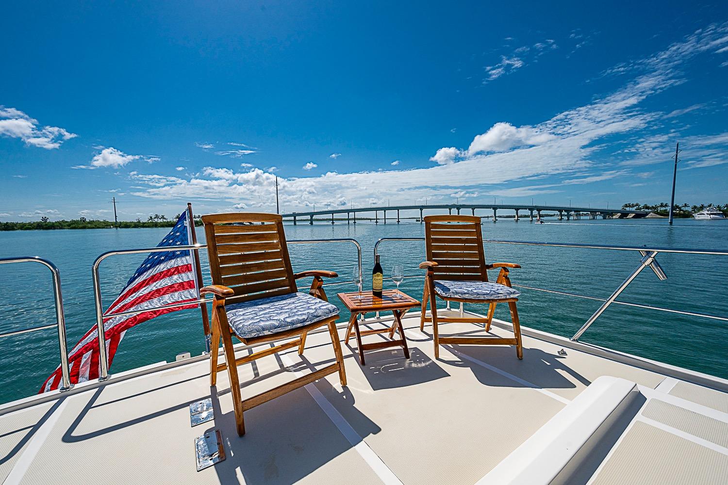 Deck of 2014 Marlow 80 Explorer yacht with chairs, table, and American flag.
