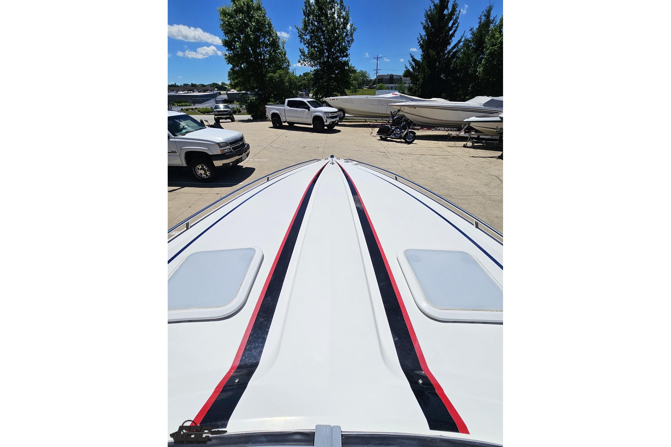 2005 Formula 271 FASTech boat with sleek design, parked near vehicles and trees.