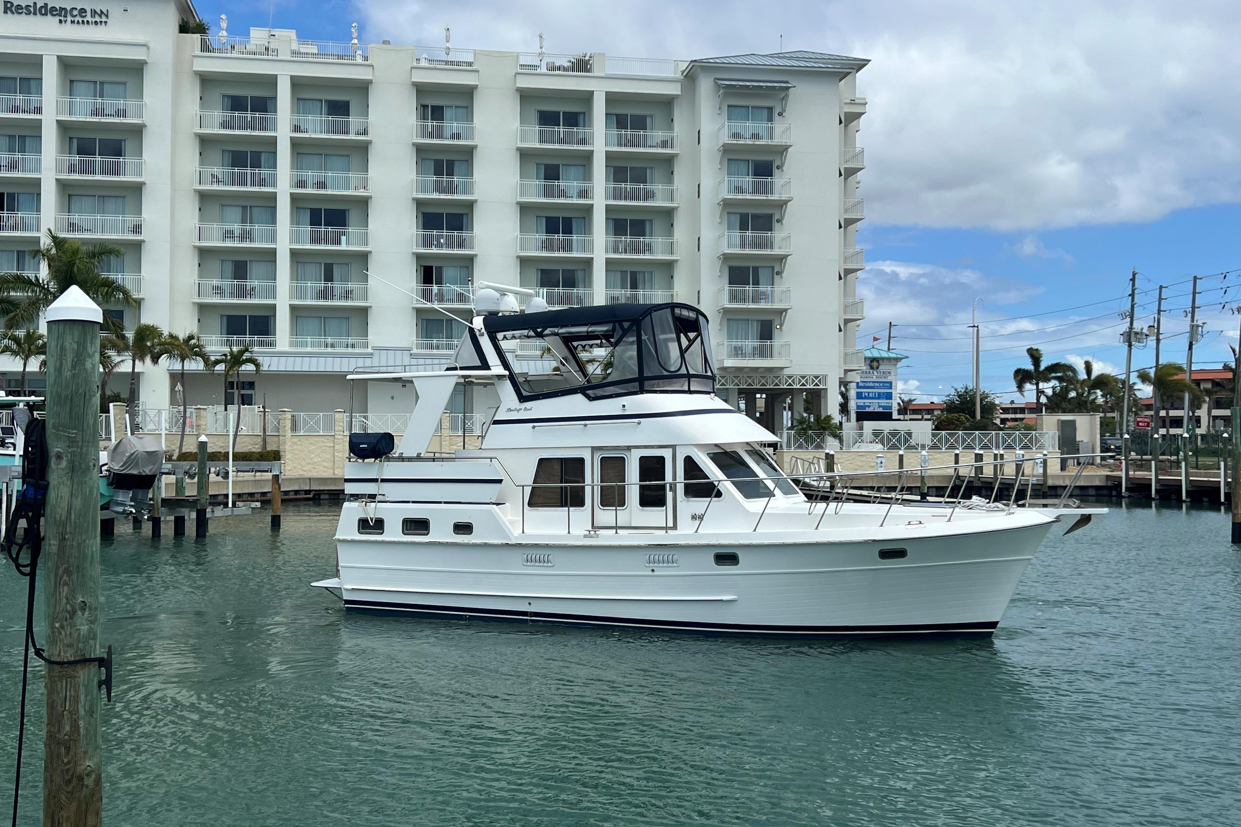 2007 Heritage East 36 Sundeck Trawler docked near a waterfront hotel.