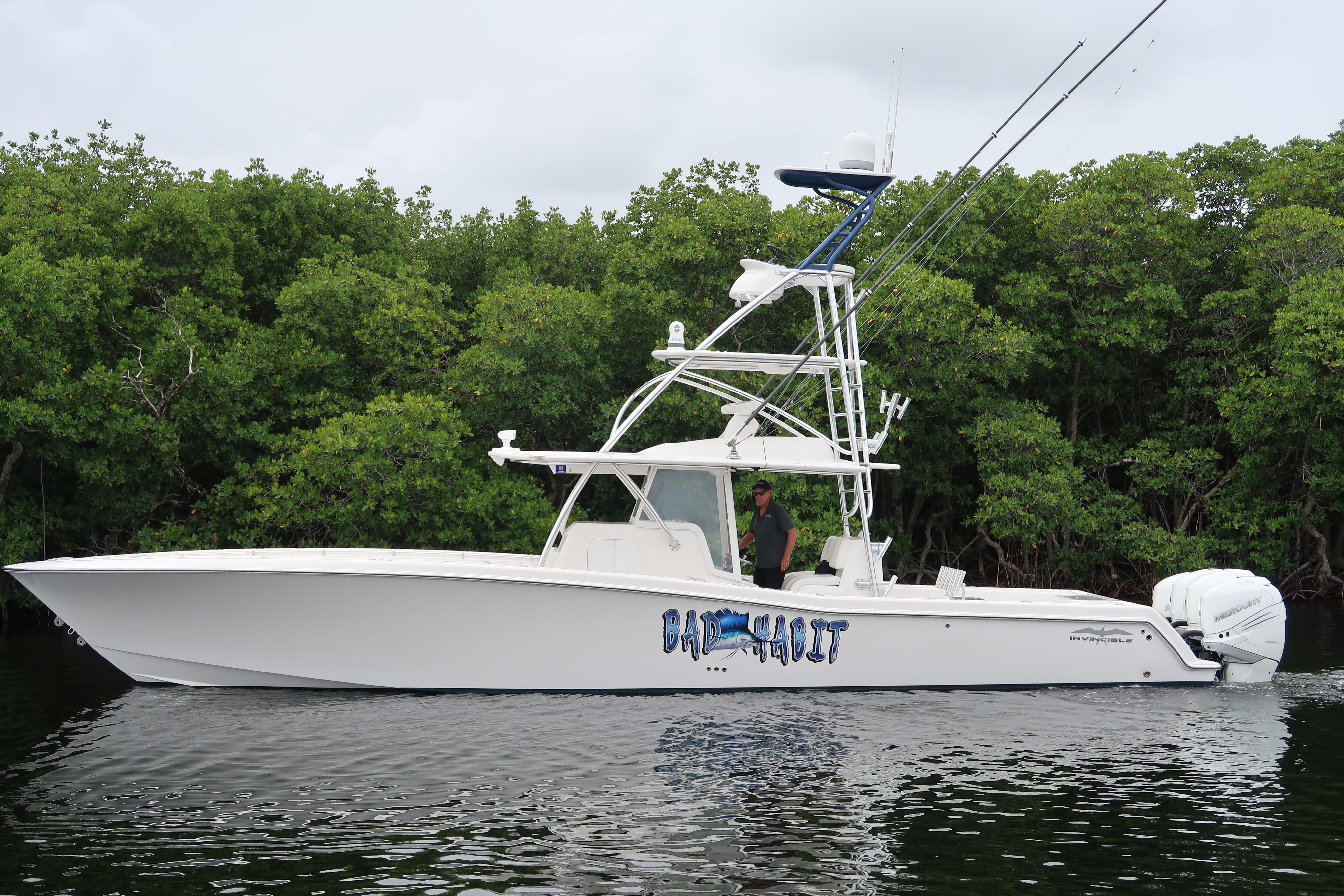 2016 Invincible 42 Open Fisherman boat on calm water near lush green trees.