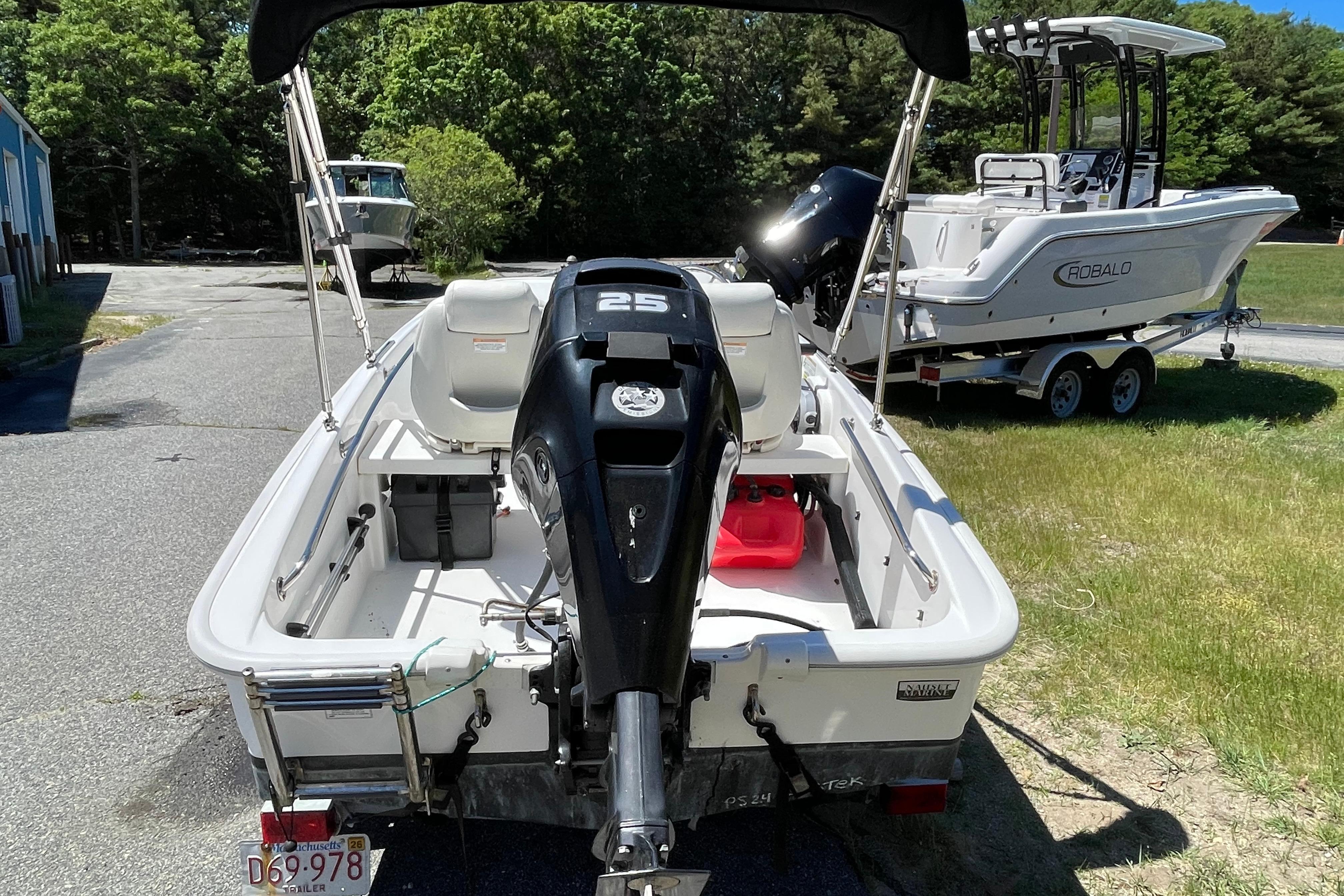 2017 Boston Whaler 130 Super Sport boat with outboard motor, parked on grass.