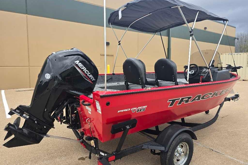 2026 Tracker Pro Guide V-16 SC boat with Mercury engine, red exterior, parked on trailer.