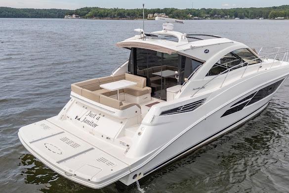2016 Sea Ray Sundancer 510 yacht cruising on a serene lake with lush green shoreline.