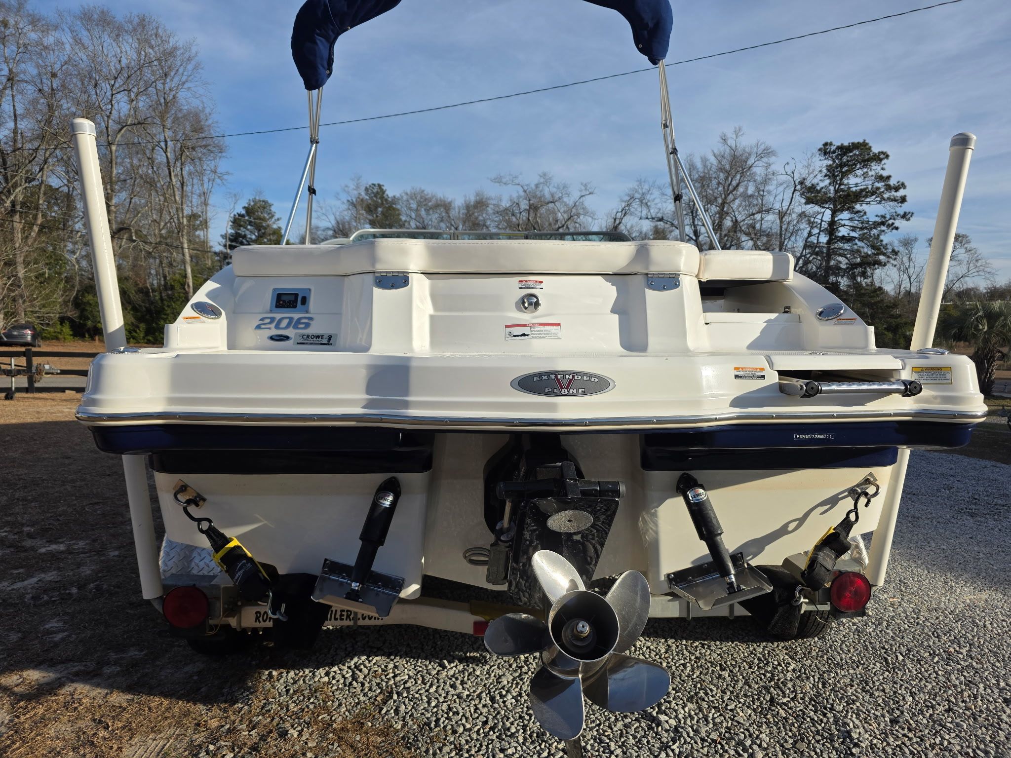The rear of a white Chaparral 206 SSi boat on a gravel path.