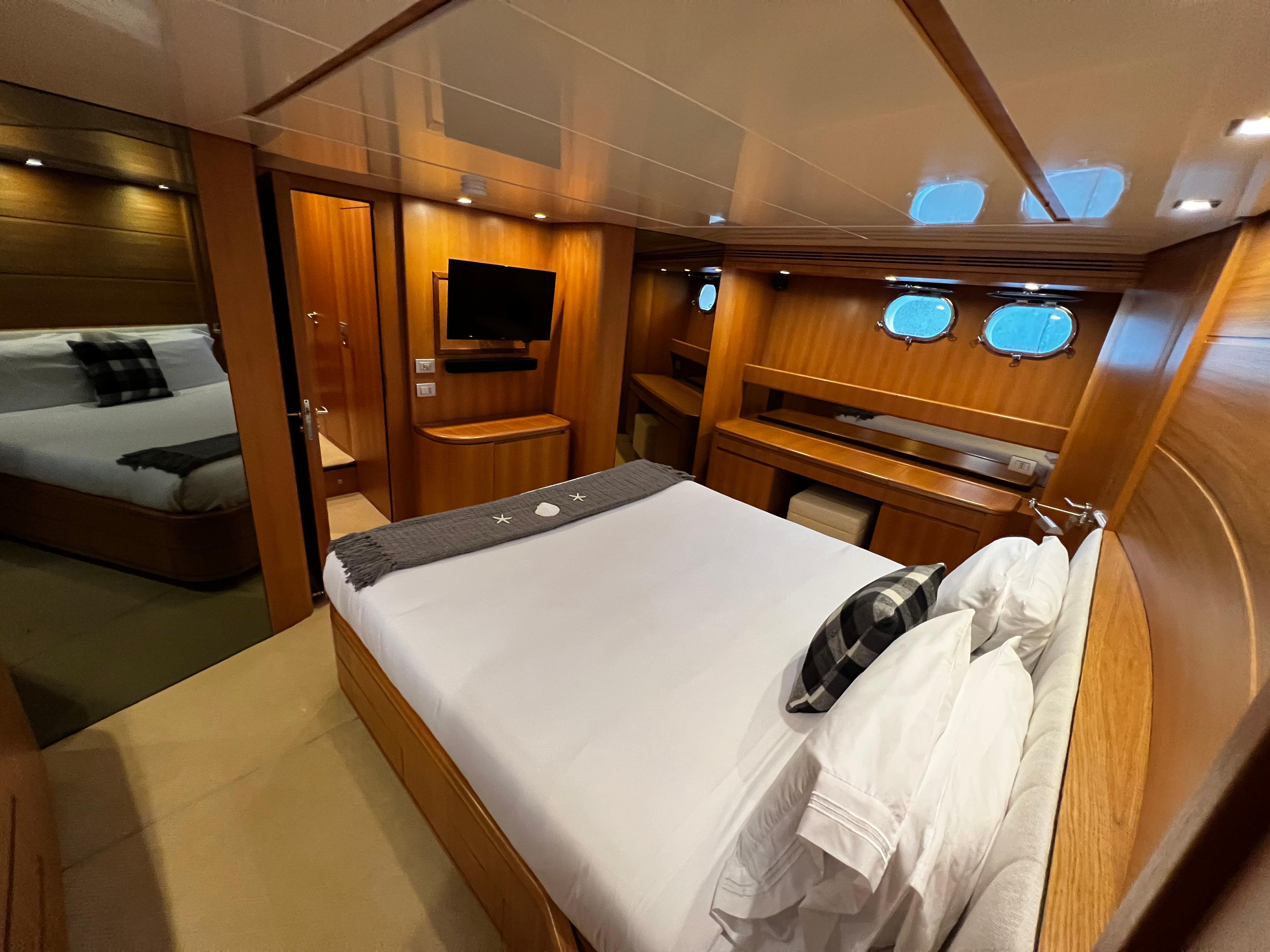 Luxurious bedroom on a 2006 Sanlorenzo SL72 yacht with wood paneling and modern amenities.