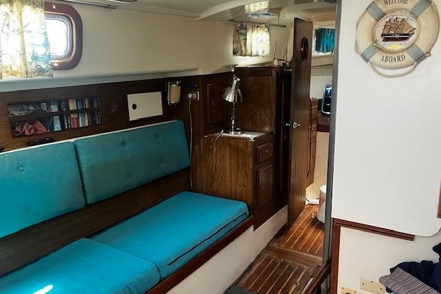 Interior of a 1979 Pearson 365 Ketch sailboat with teal cushions and wooden cabinetry.