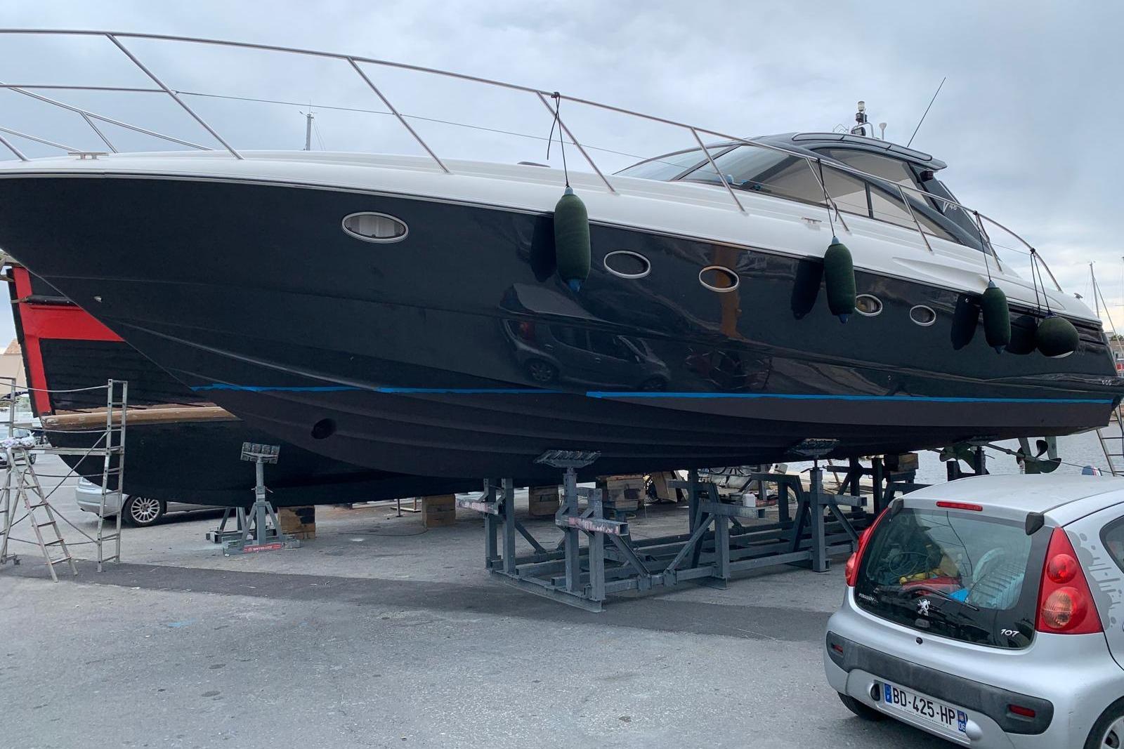 2006 Princess V48 yacht on dry dock, with a car nearby.