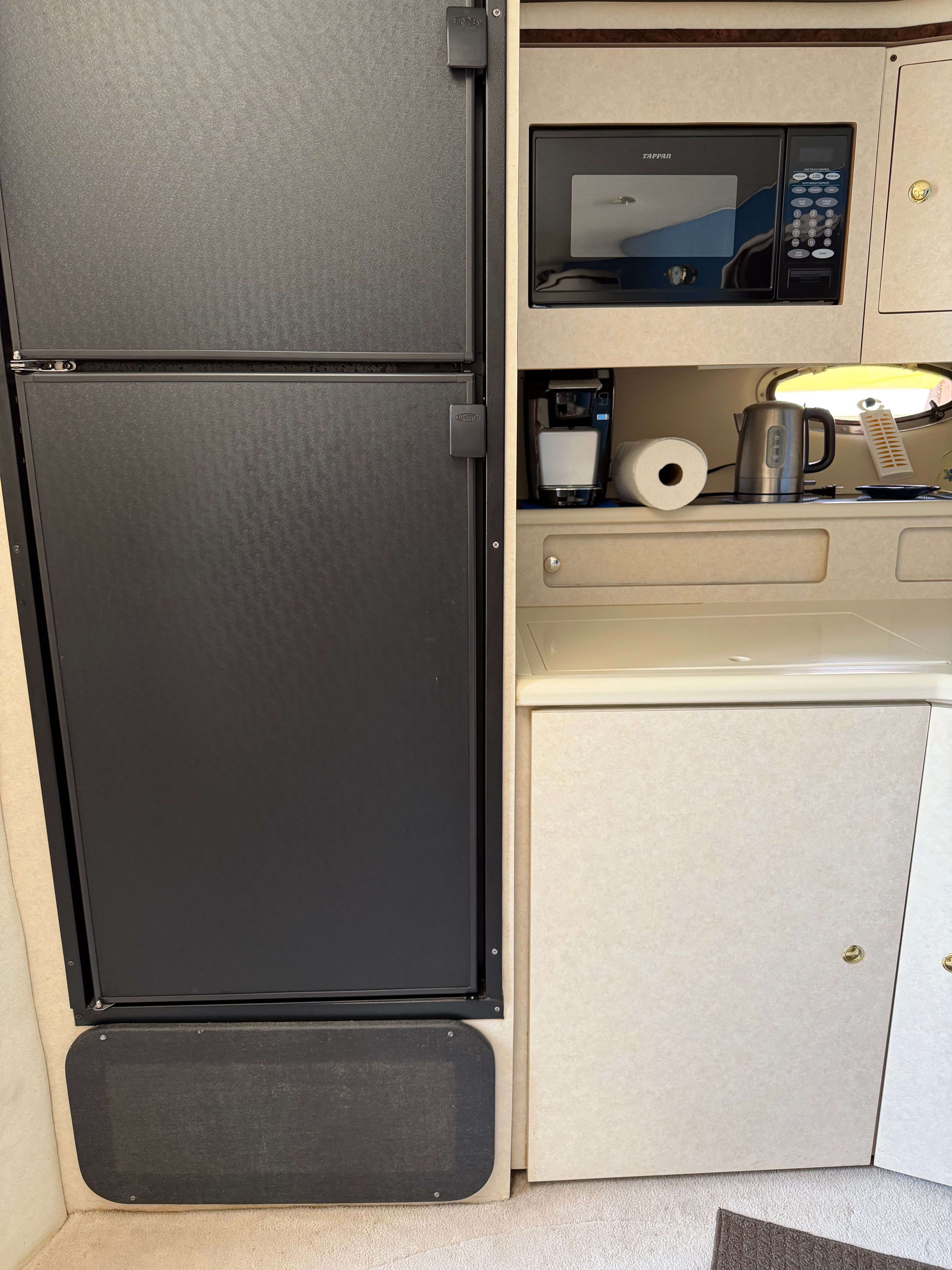 Kitchen area of a 1997 Regal Commodore with fridge and microwave.