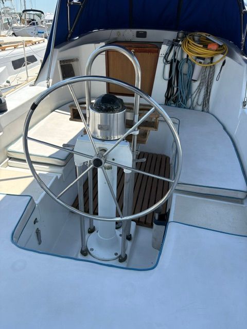 Steering wheel of a 1983 C&C Landfall with clean deck and ropes in the background.