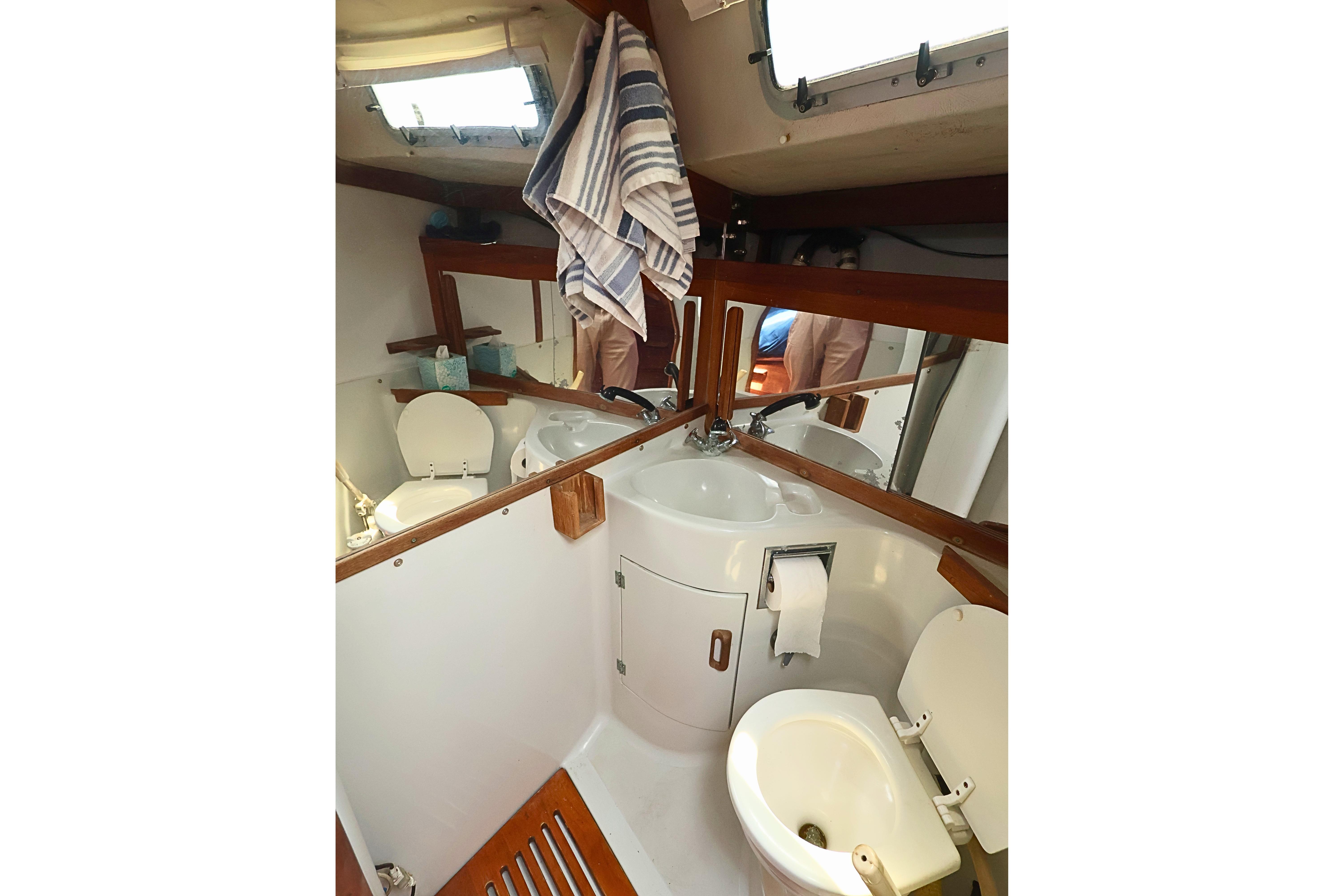 Compact bathroom in 1989 J Boat J 40, featuring sink, toilet, and mirrors.