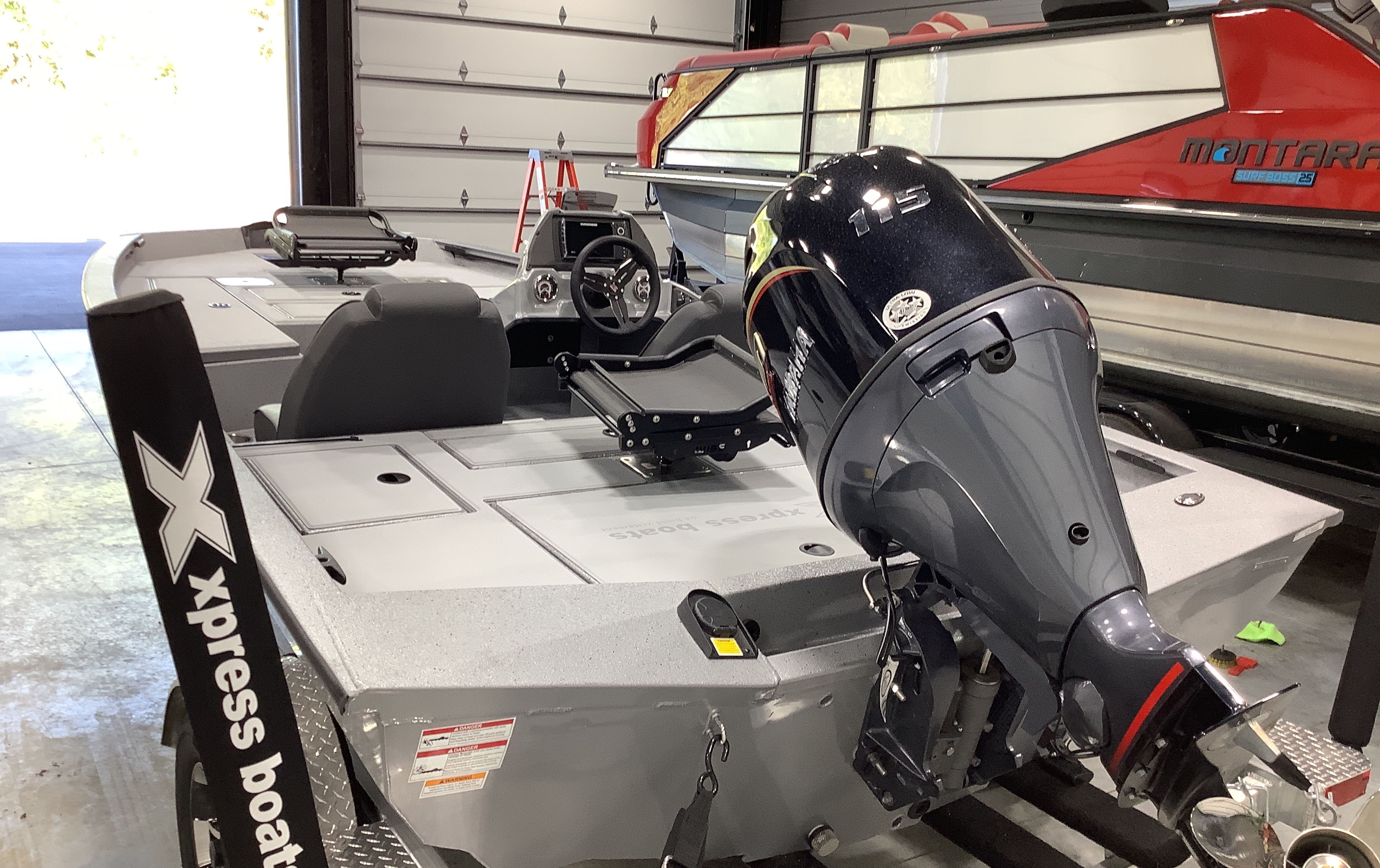 2026 Xpress Boats H18C with outboard motor in garage.