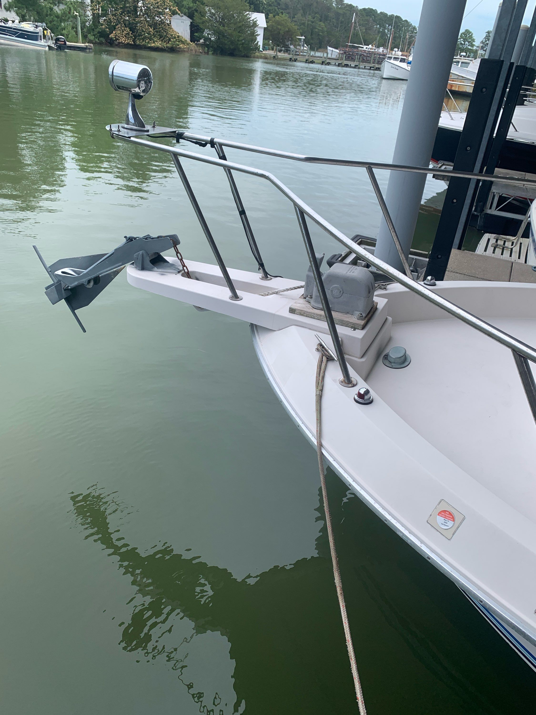 Bow of a 1987 Wellcraft COASTAL with anchor windlass and railing, moored on calm water.