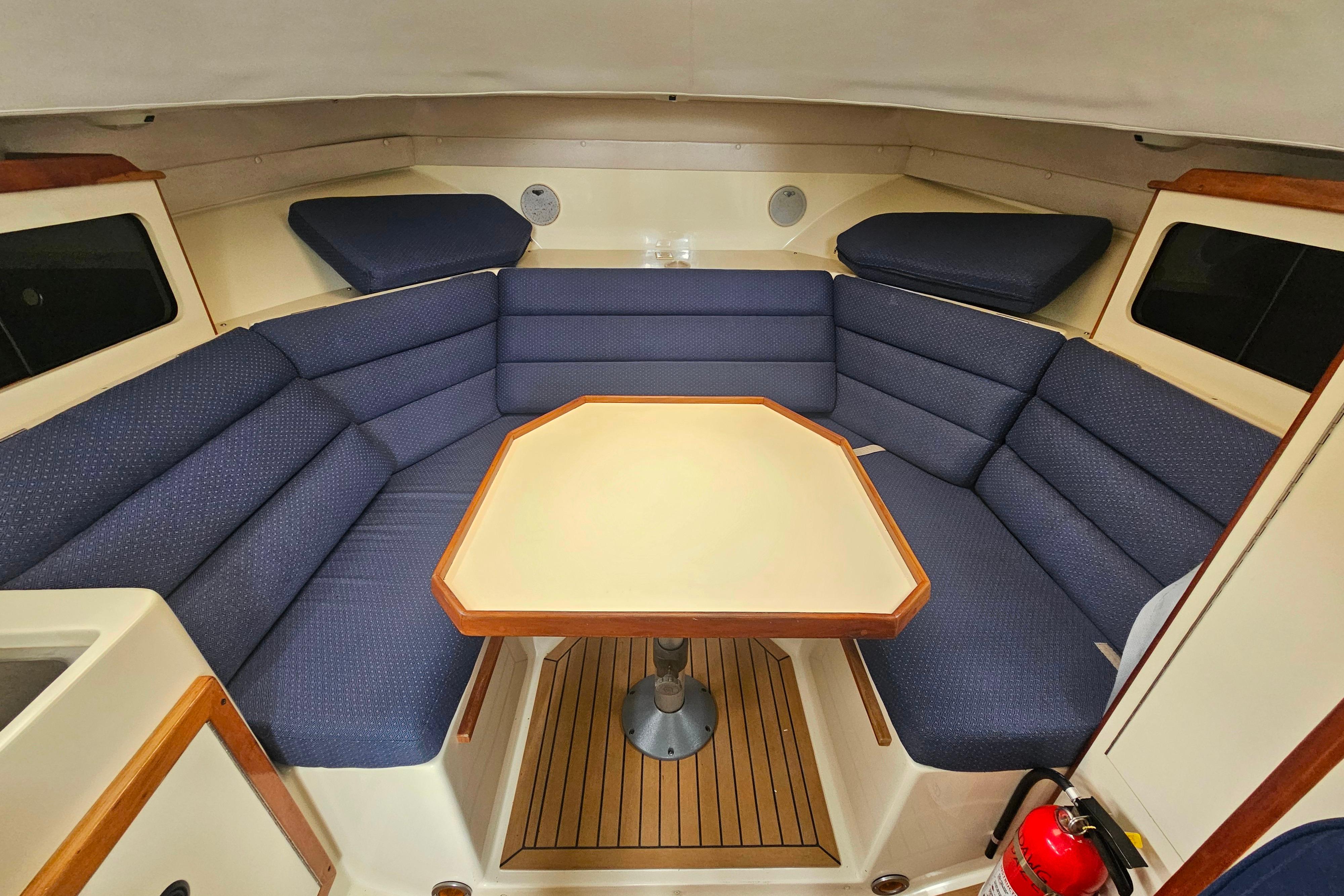 Interior of a 1999 Albin 28 Tournament Express with blue cushioned seating and a central table.
