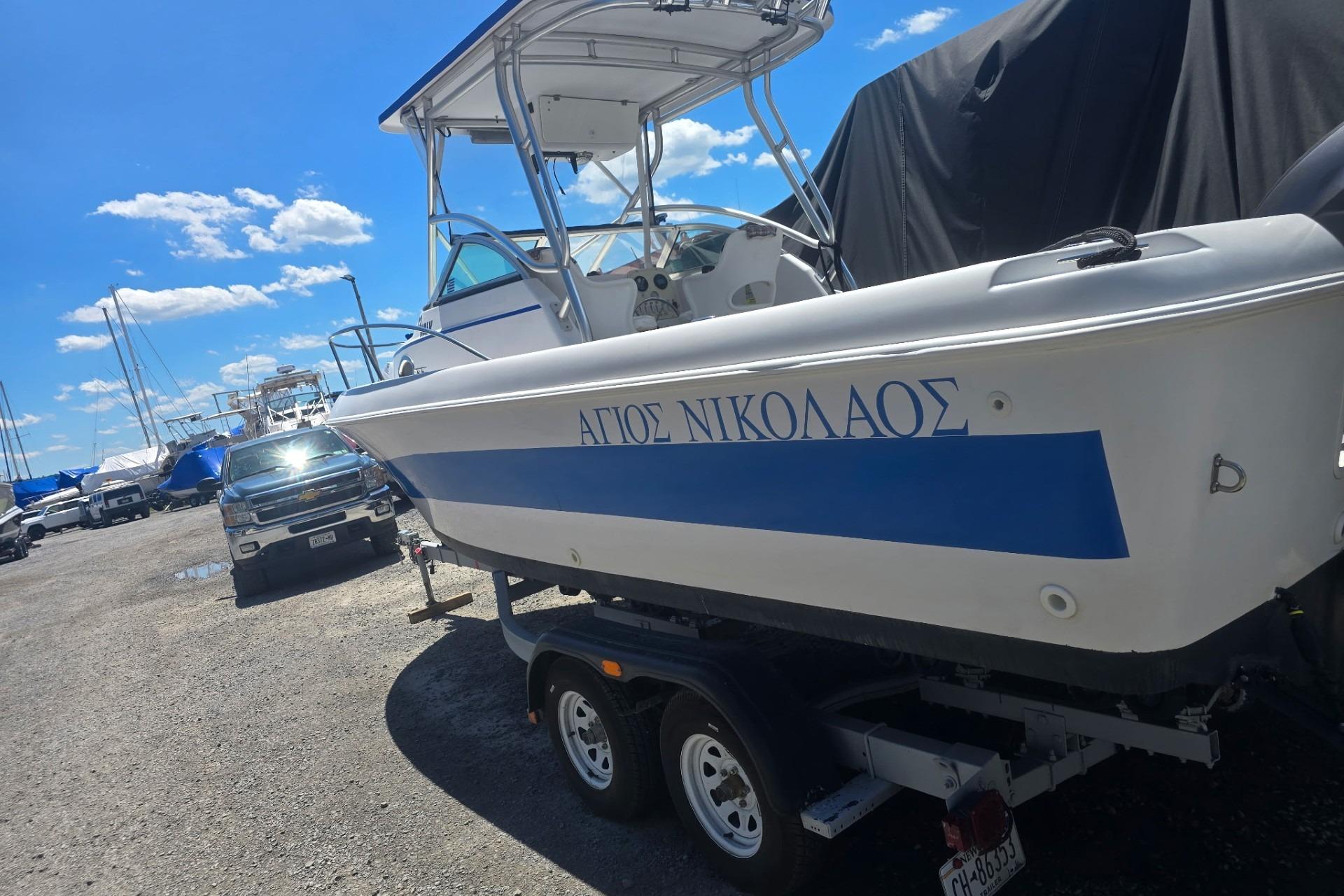 2003 Pro-Line 22 Walkaround boat on trailer, parked outdoors under a clear blue sky.