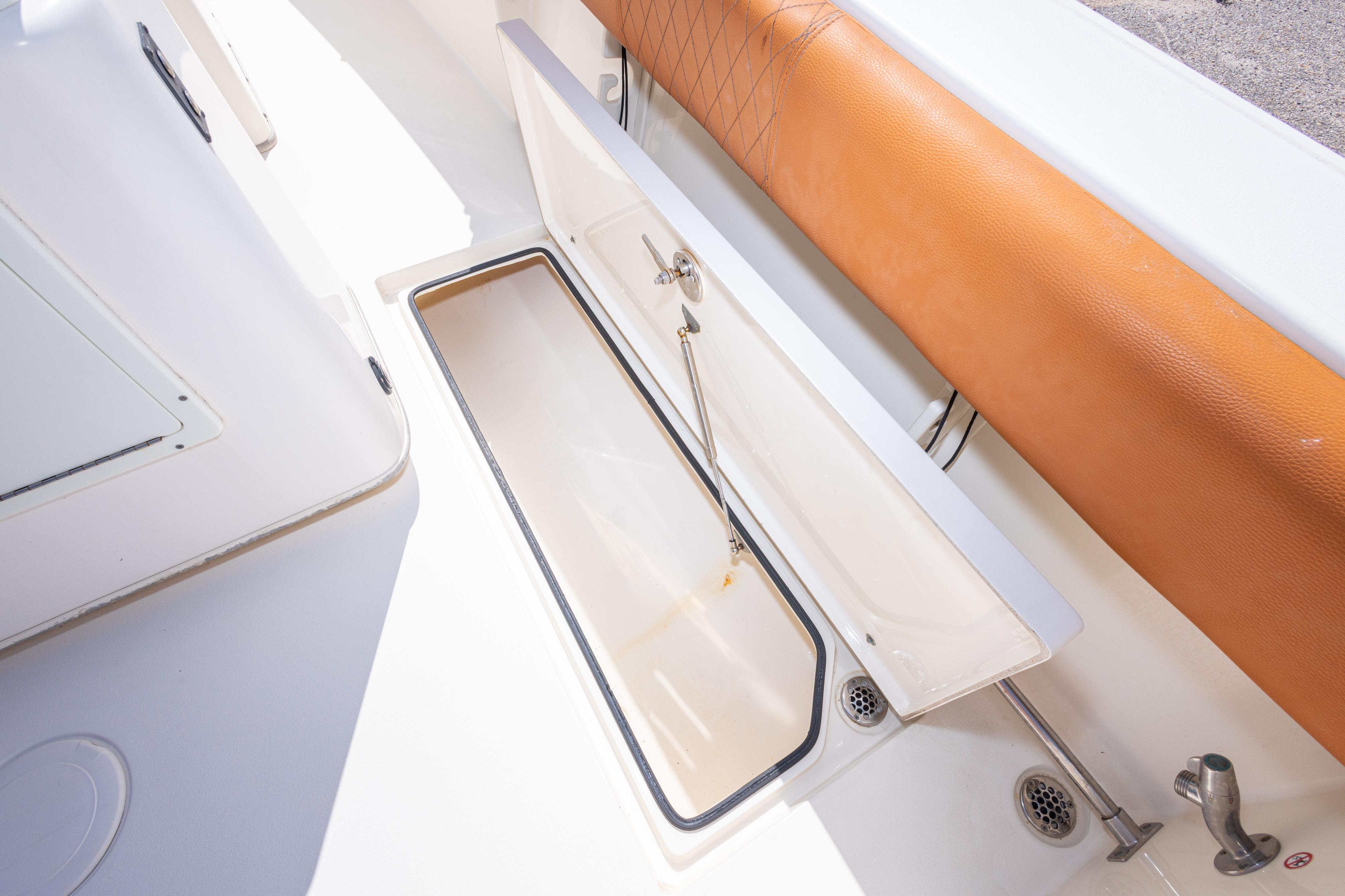 2017 Cobia 261 Center Console boat storage compartment with tan cushion and white interior.