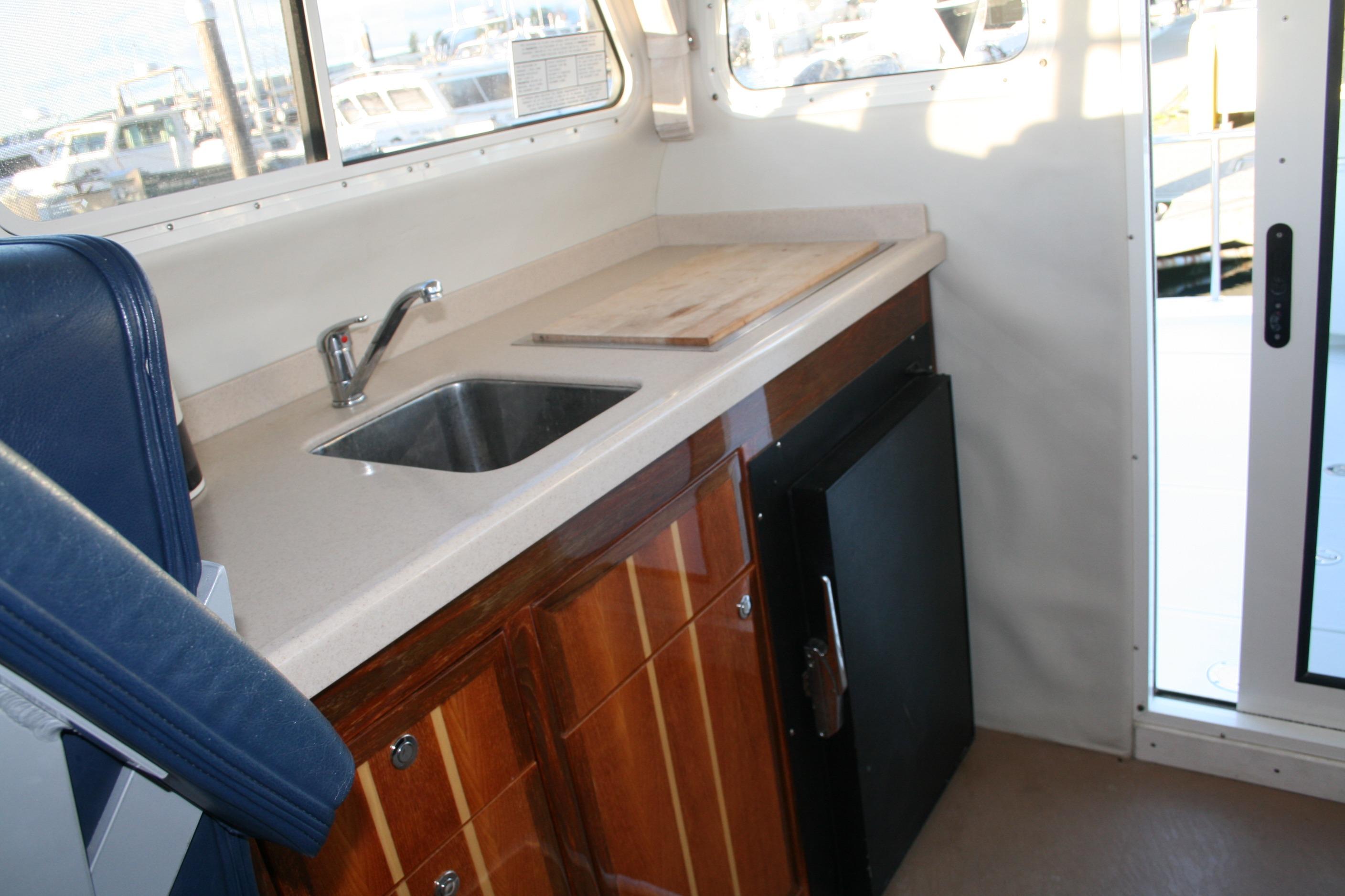 Interior of 2005 Ocean Sport 30' boat with sink, countertop, and wooden cabinets.