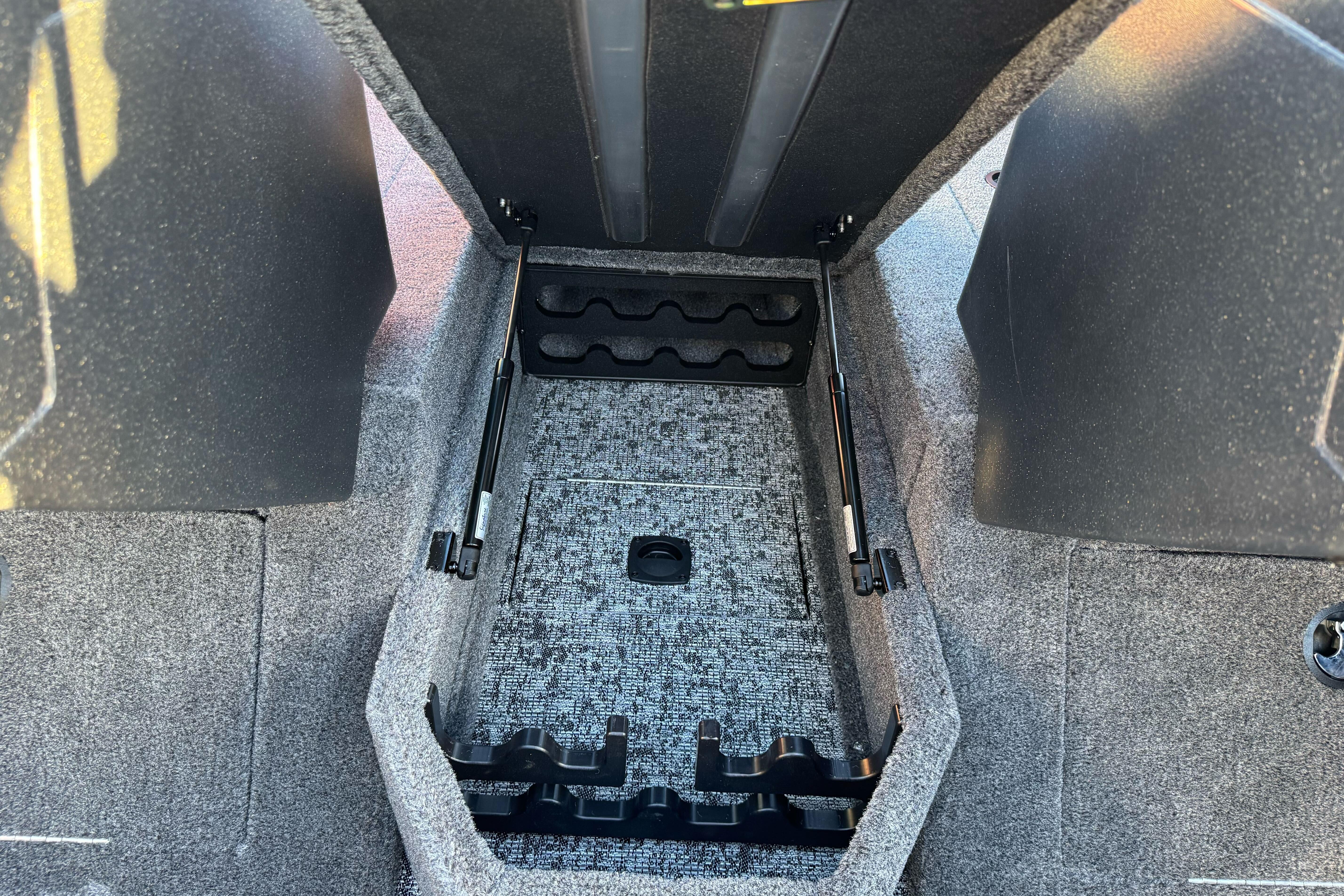 2026 Tracker Targa V-18 WT boat storage compartment with carpeted interior and rod holders.