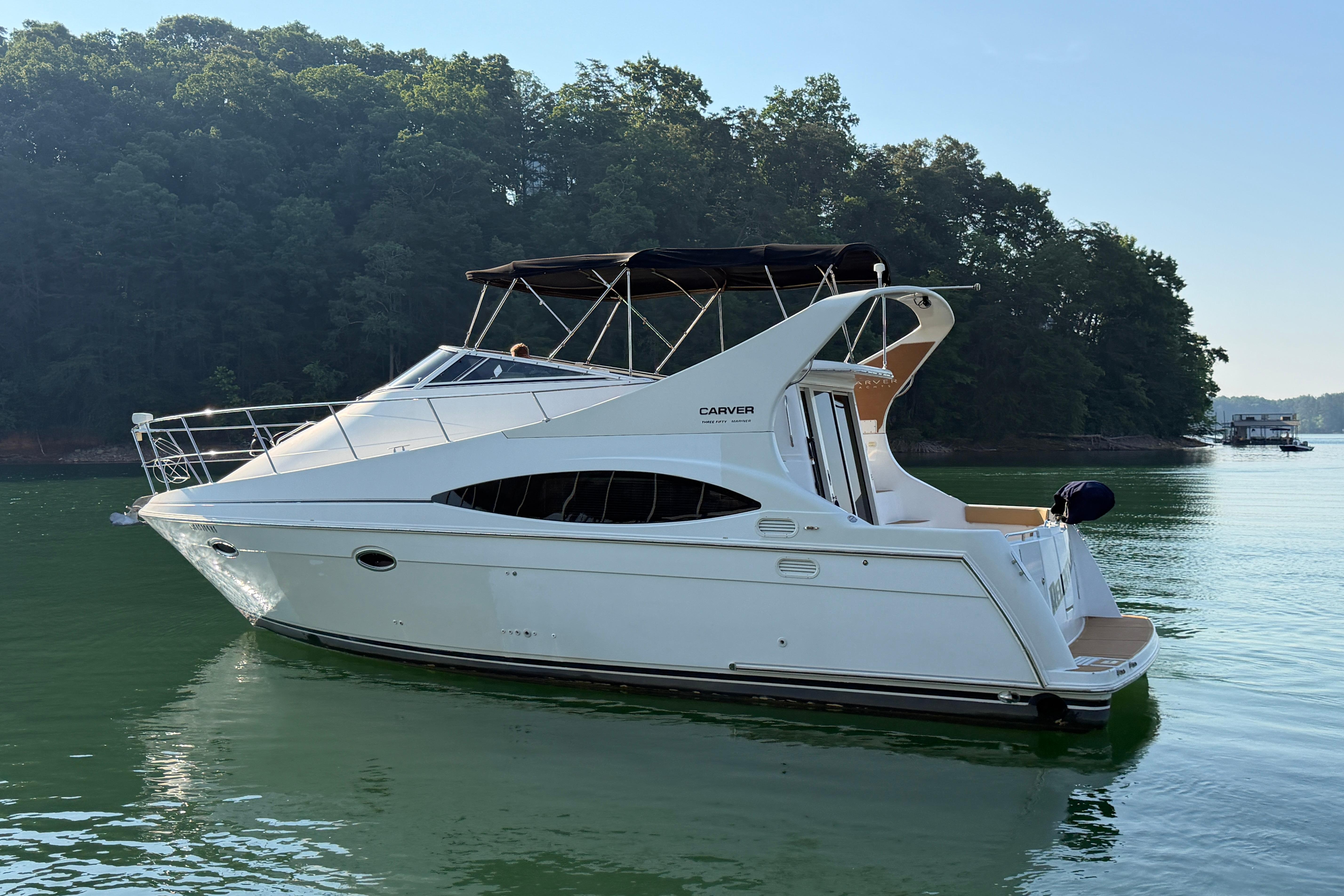 2003 Carver 350 Mariner yacht on calm water, surrounded by lush trees.