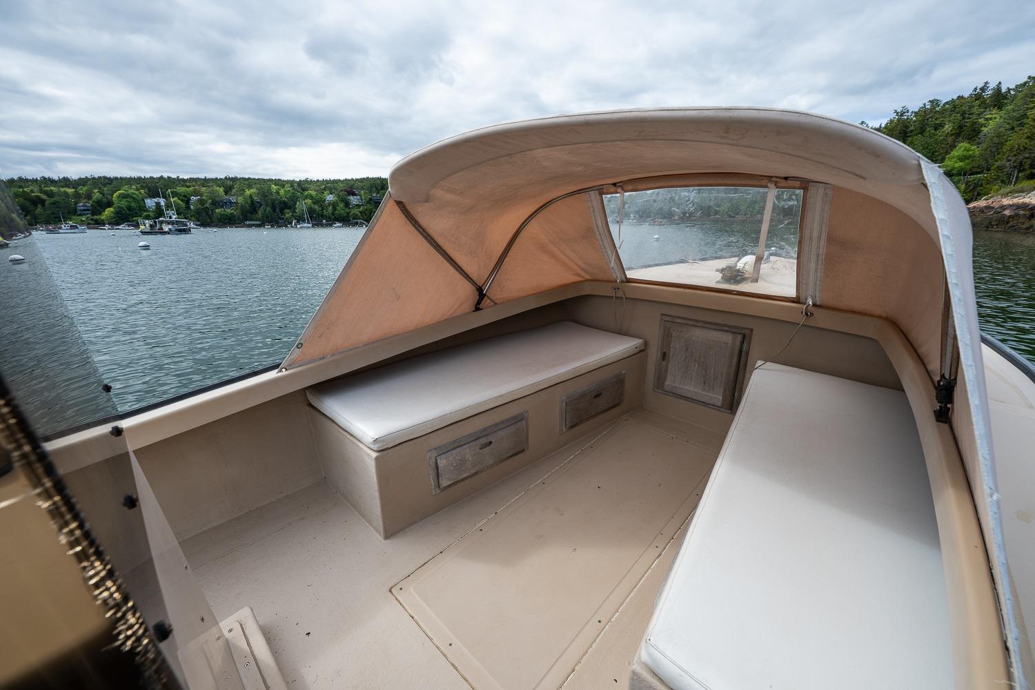 1989 Ellis 24 Open boat interior with cushioned seating, docked on a scenic lake.